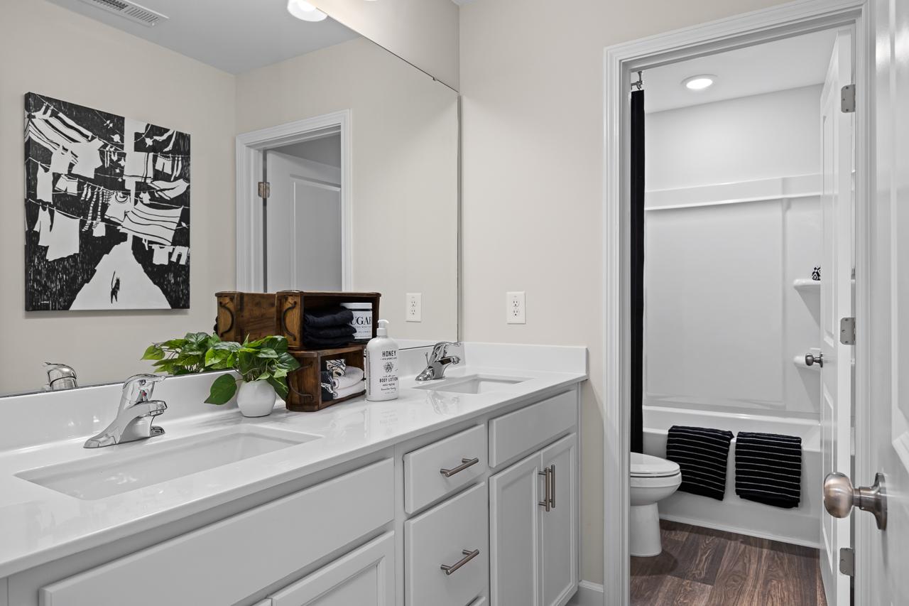 Spacious modern bathroom at Wellers Knoll in Lillington NC with white double vanity, soaking tub, and abstract art