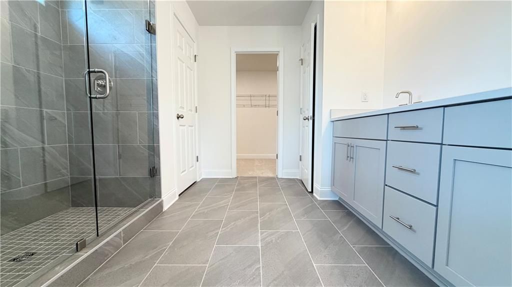 Modern primary bathroom with glass shower and dual vanity in The Hickory C floor plan, Wehunt Meadows, Hoschton, Georgia.