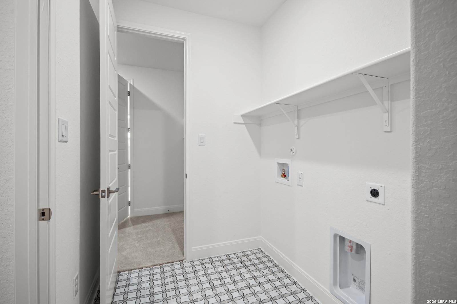Laundry room with patterned tile flooring and shelving in The Lanier G floor plan at Potranco Oaks, Castroville, Texas.