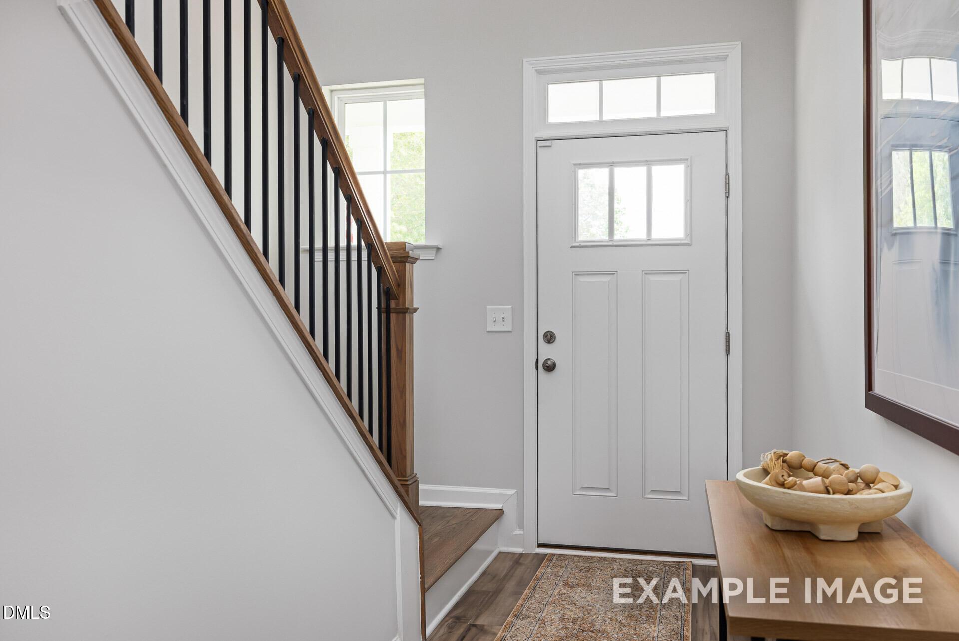 Foyer with wooden staircase and white front door in The Adalynn A floor plan by Davidson Homes in Zebulon, North Carolina.