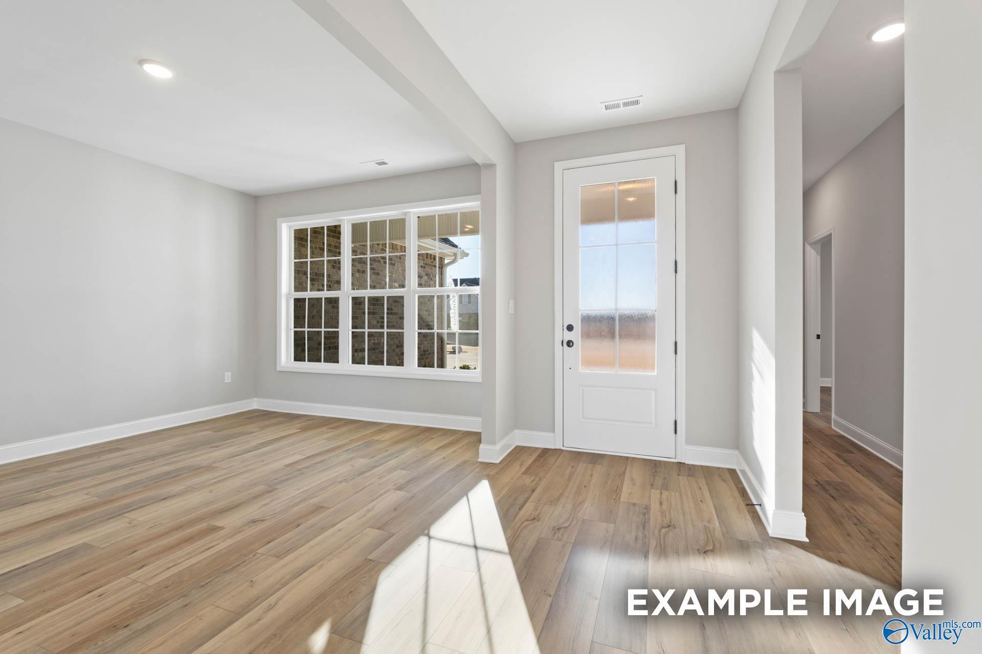 Bright entry foyer with hardwood floors, large windows, and glass door in Davidson Homes The Valencia, Meridianville AL