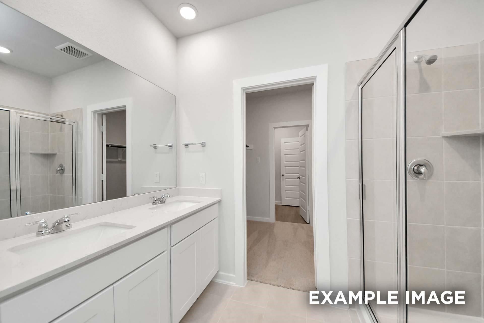 Bright master bathroom with double vanity, large mirror, and tiled walk-in shower in Davidson Homes Blanco E, Magnolia, TX
