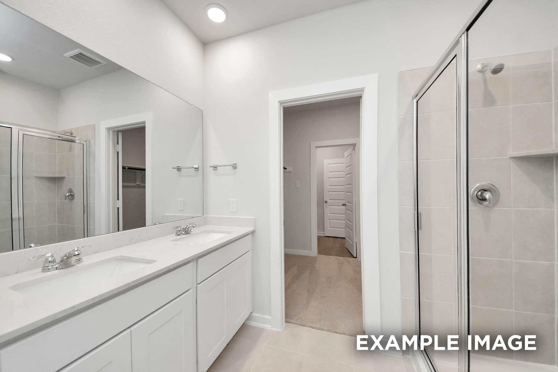 Bright master bathroom with double vanity, large mirror, and tiled walk-in shower in Davidson Homes Blanco E, Magnolia, TX