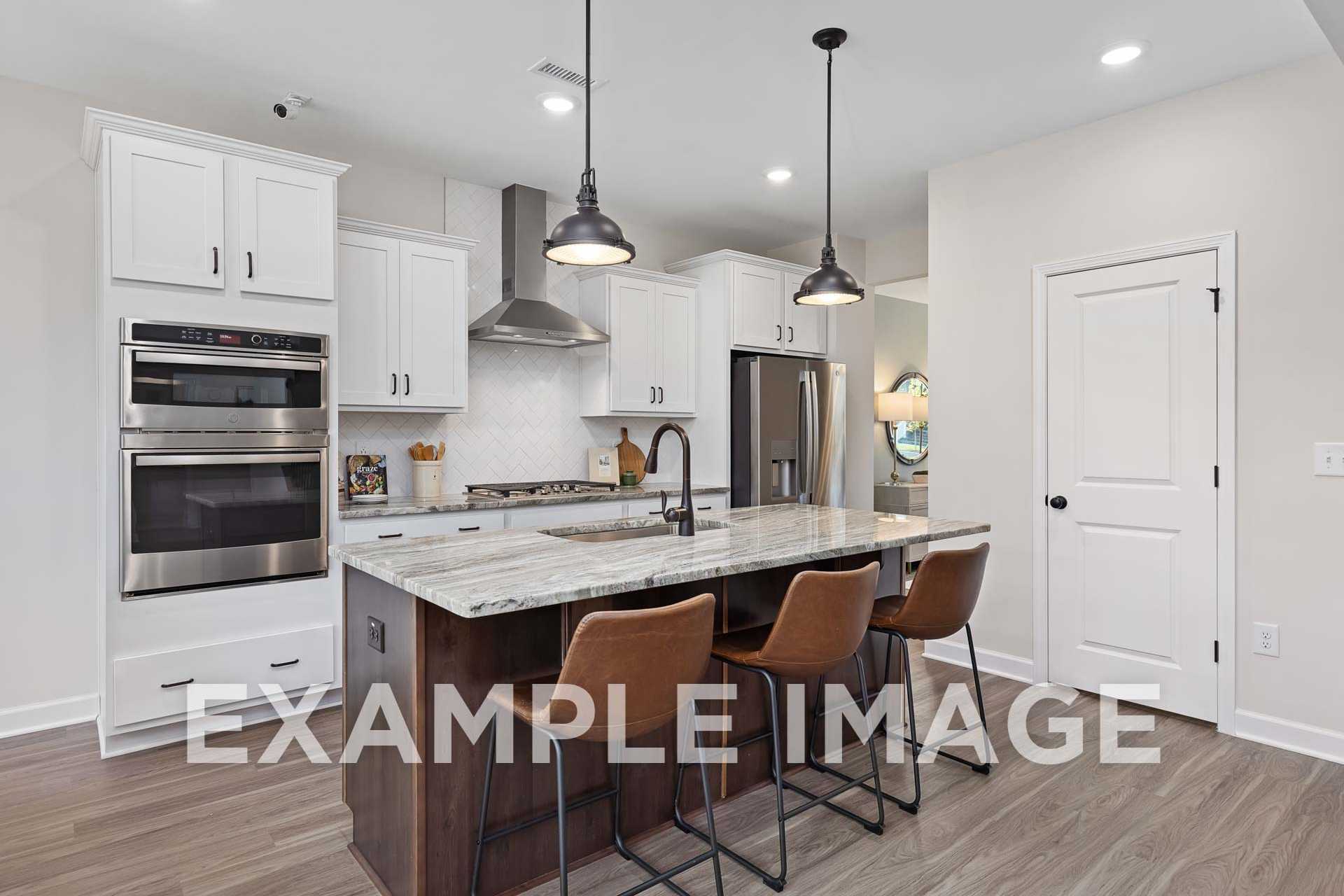 Modern kitchen in The Willow F featuring white shaker cabinets, stainless steel appliances, quartz island, and pendant lights