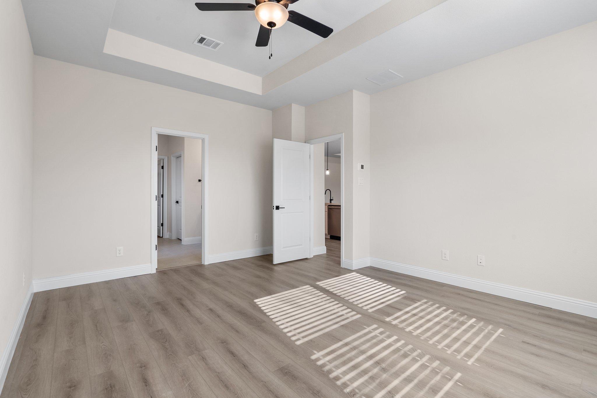 Spacious primary bedroom with tray ceiling and wood-look flooring in The Holly F home design by Davidson Homes.