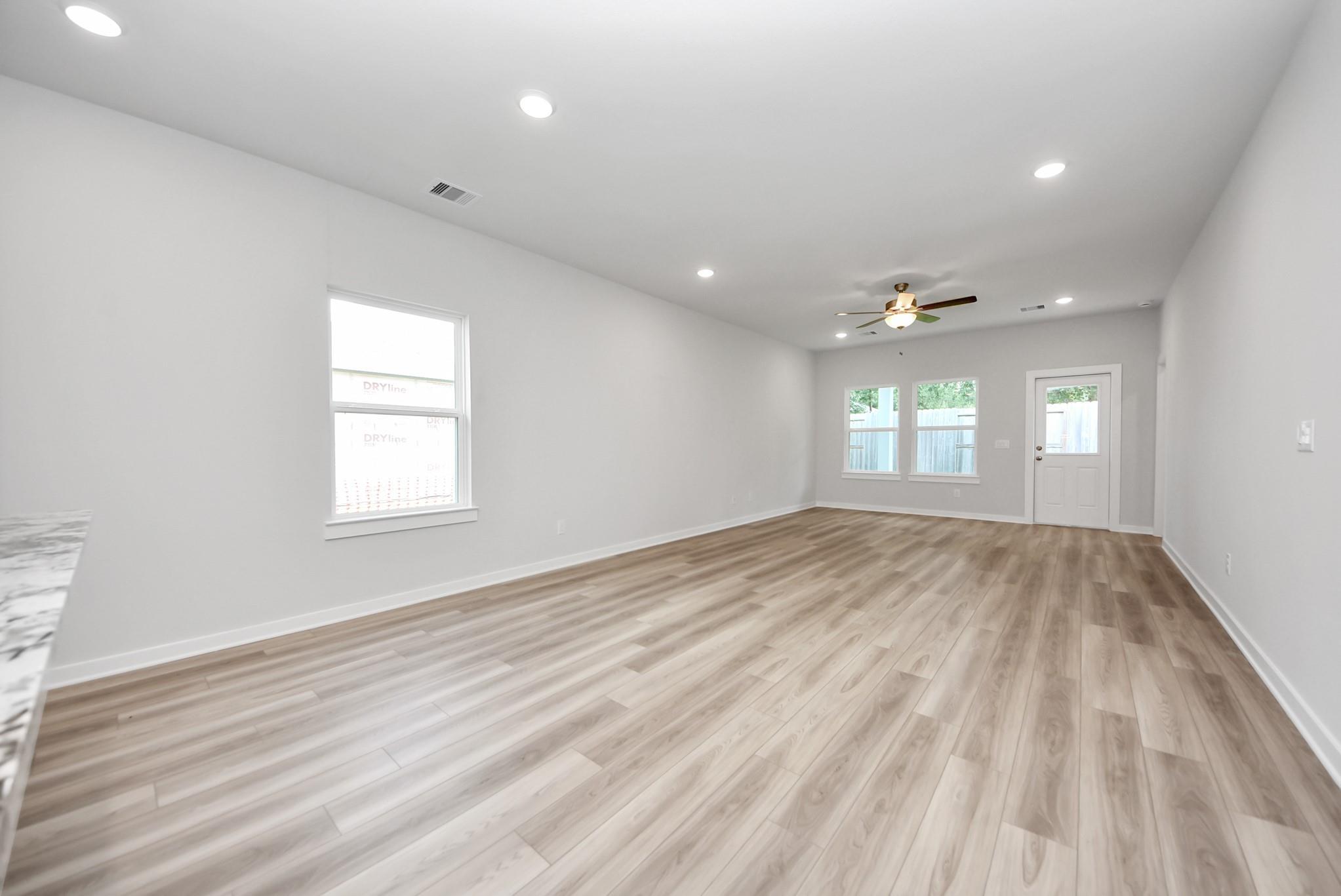 Spacious open-concept living area with wood-look flooring in The Sabine E floor plan at Windmill Estates, Magnolia, Texas.