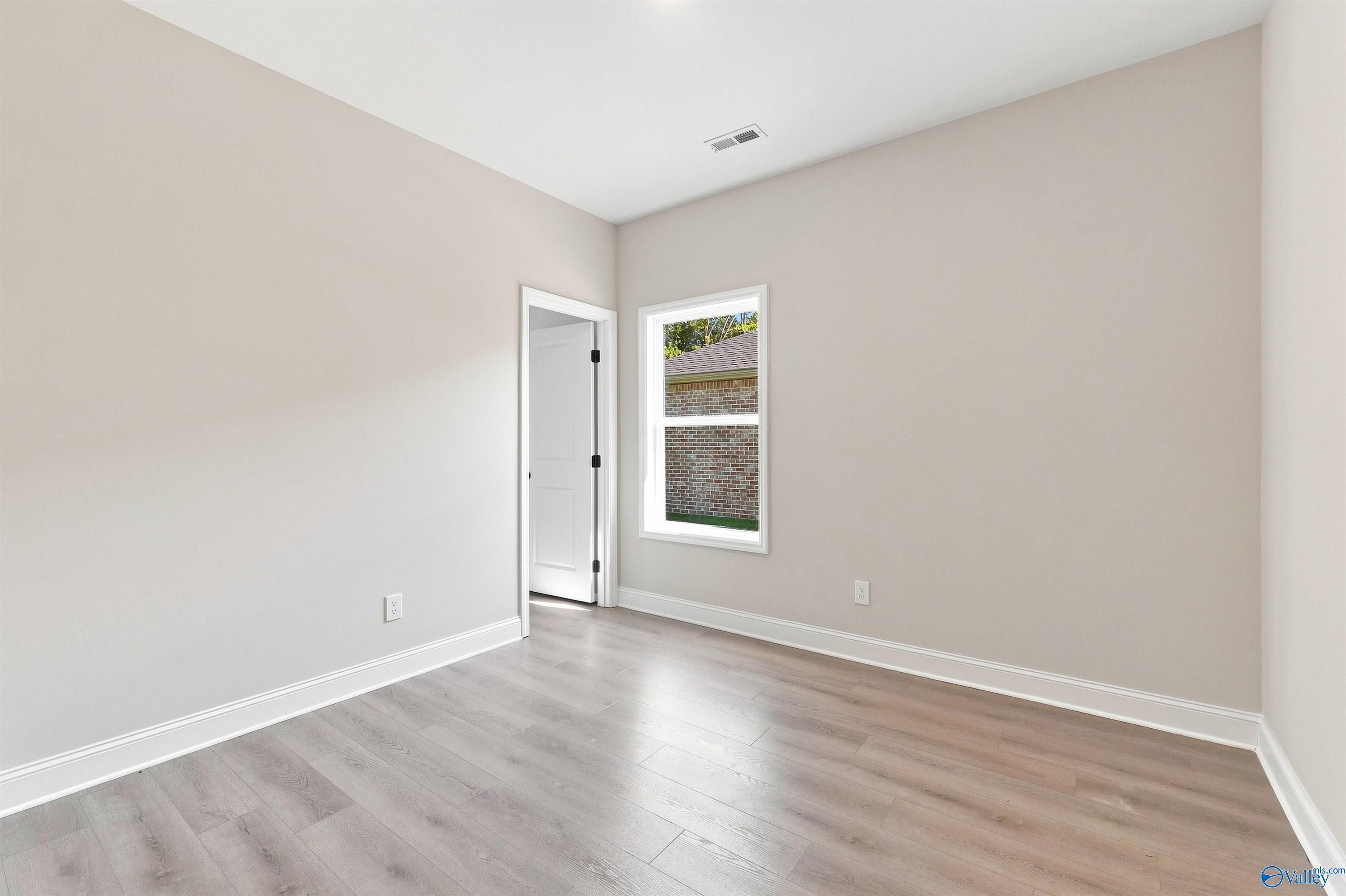 Bright, neutral-toned bedroom with wood-look flooring in The Daphne floor plan by Davidson Homes in Huntsville, Alabama.