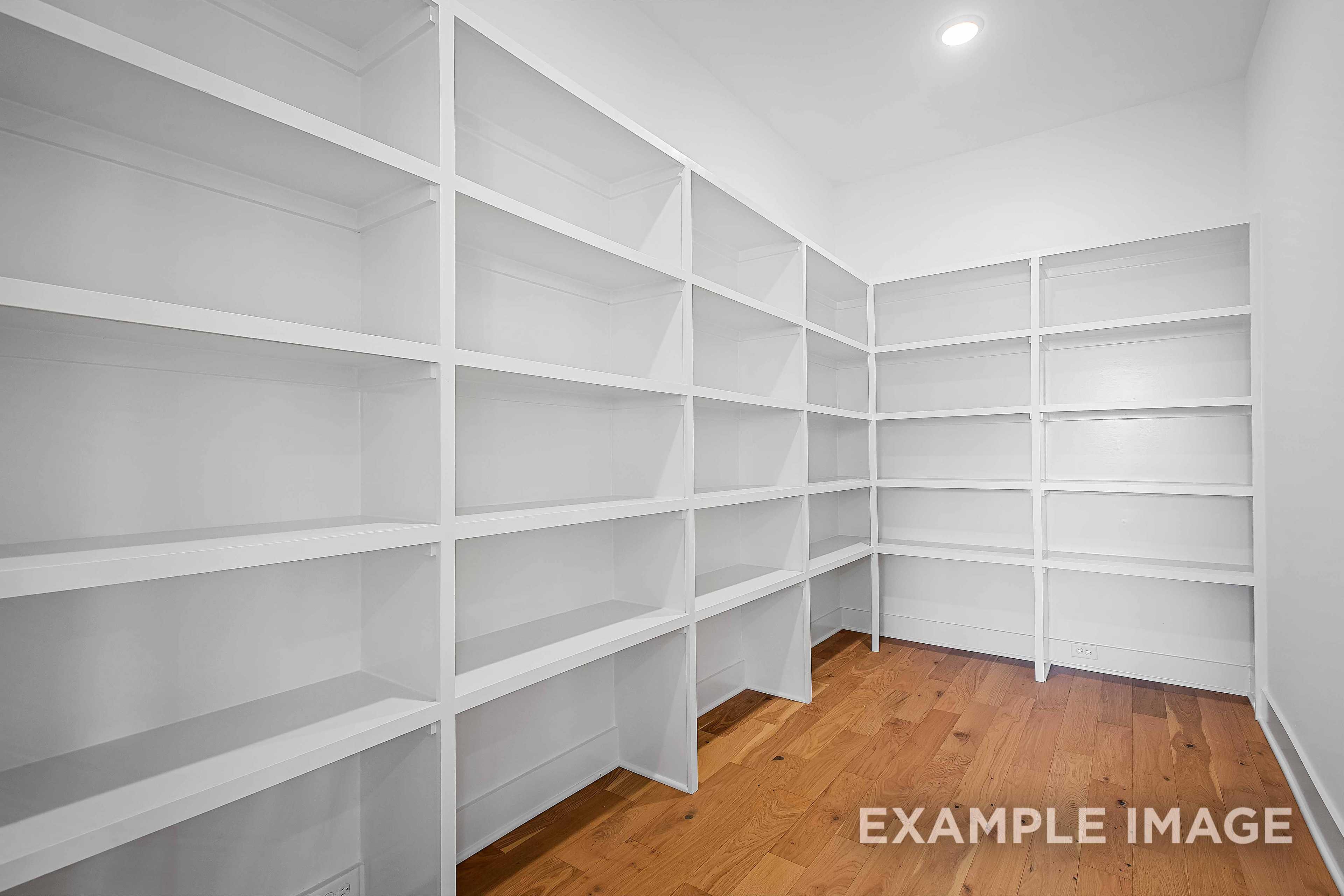 Spacious walk-in closet in The Alston A home with white built-in shelves and oak hardwood floors