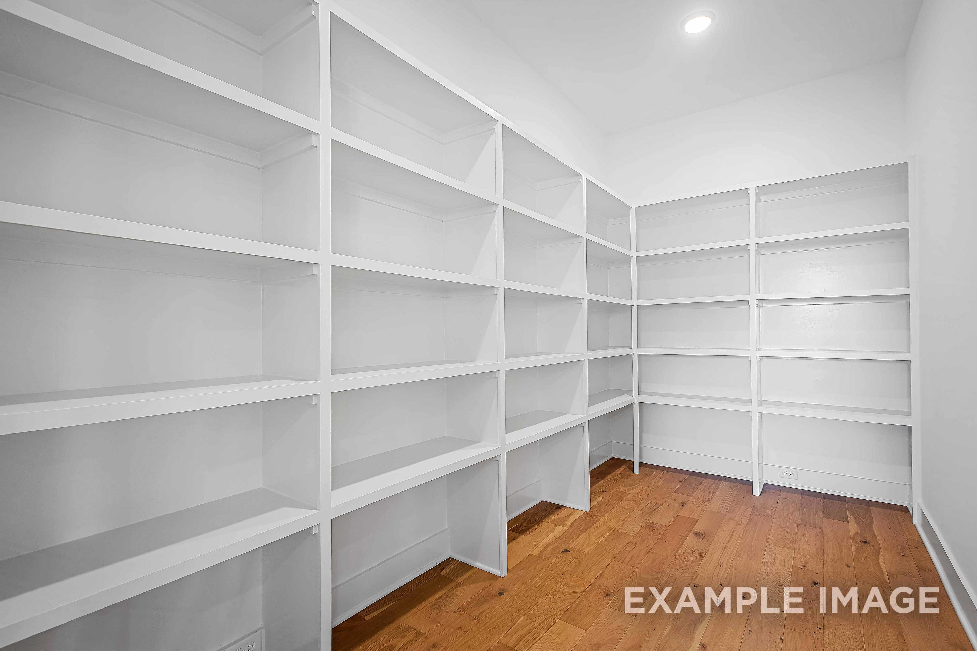 Spacious walk-in closet in The Alston A home with white built-in shelves and oak hardwood floors