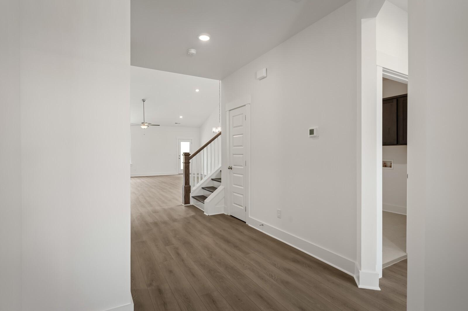 Open entryway with wood-style flooring and staircase leading to the Ridgeport C floor plan in Woods Crossing, Gallatin.
