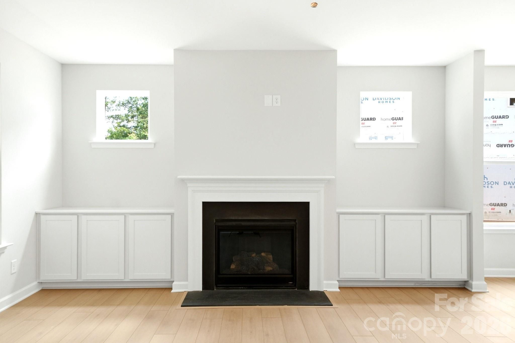 Modern fireplace with built-in white cabinets in The Magnolia B floor plan at Windgate in Mooresville, North Carolina.