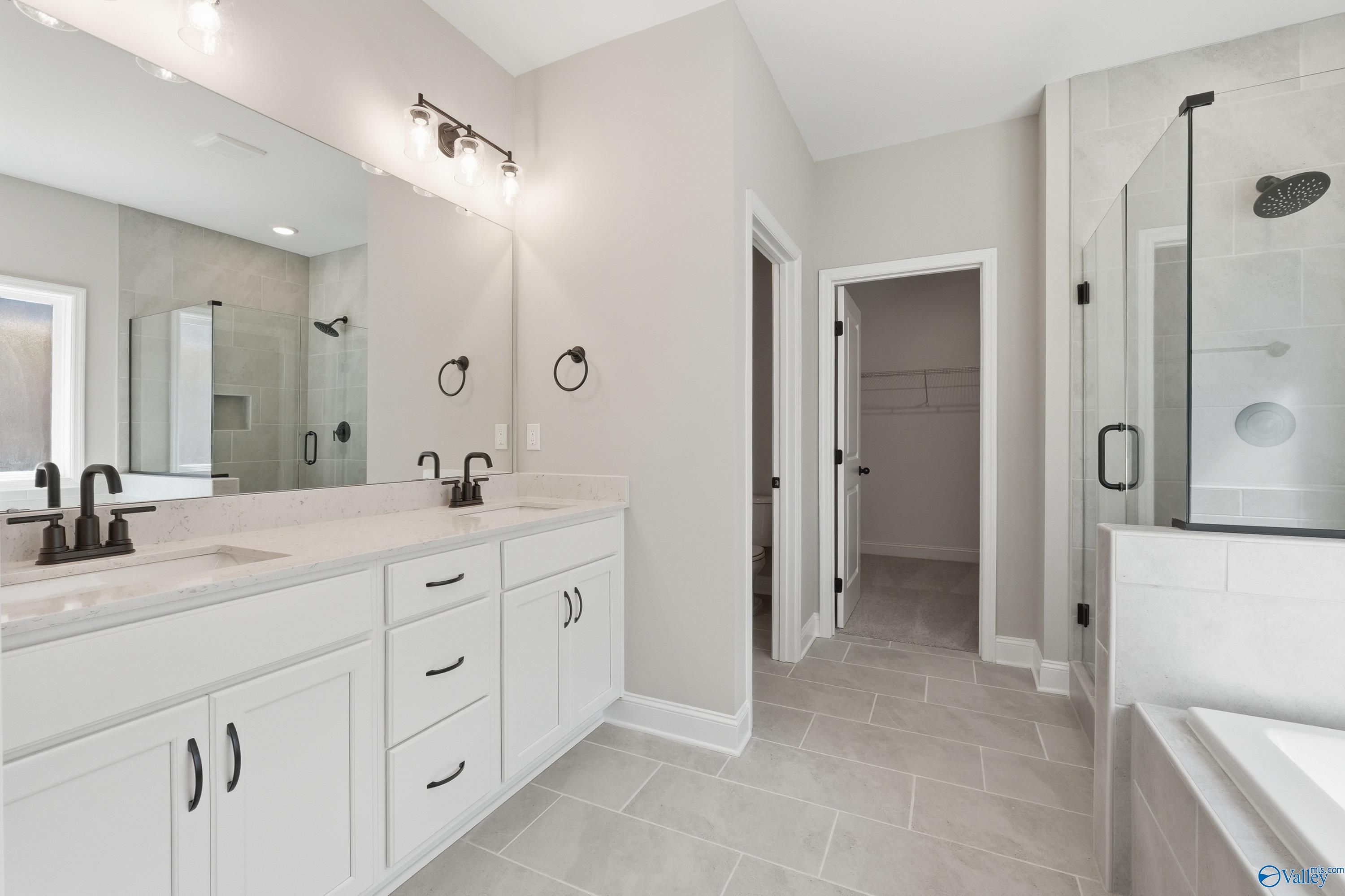 Elegant master bathroom with double white vanity, glass shower, freestanding tub in Davidson Homes The Rockford, Harvest Alabama