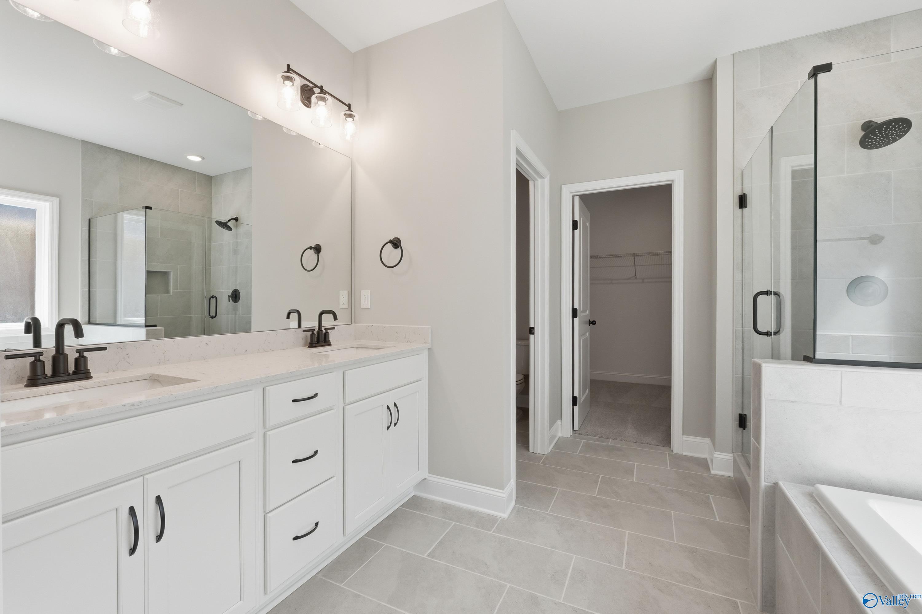 Elegant master bathroom with double white vanity, glass shower, freestanding tub in Davidson Homes The Rockford, Harvest Alabama