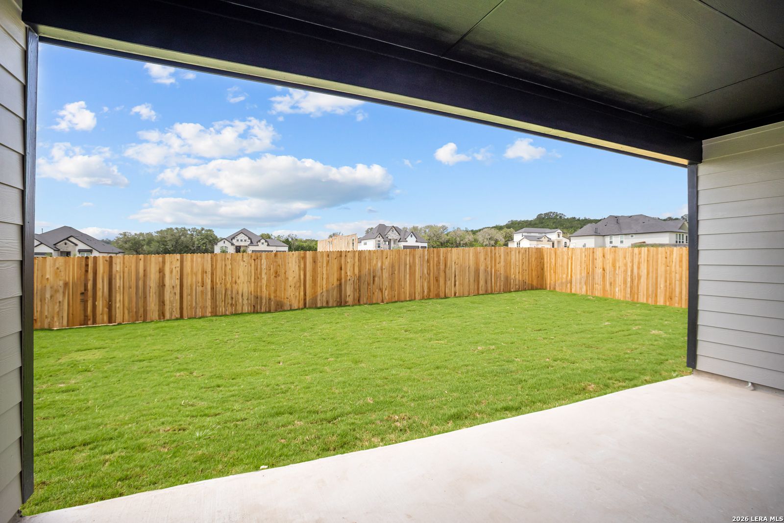 Covered patio overlooking spacious fenced backyard at The Reserve at Potranco Oaks in Castroville, Texas.