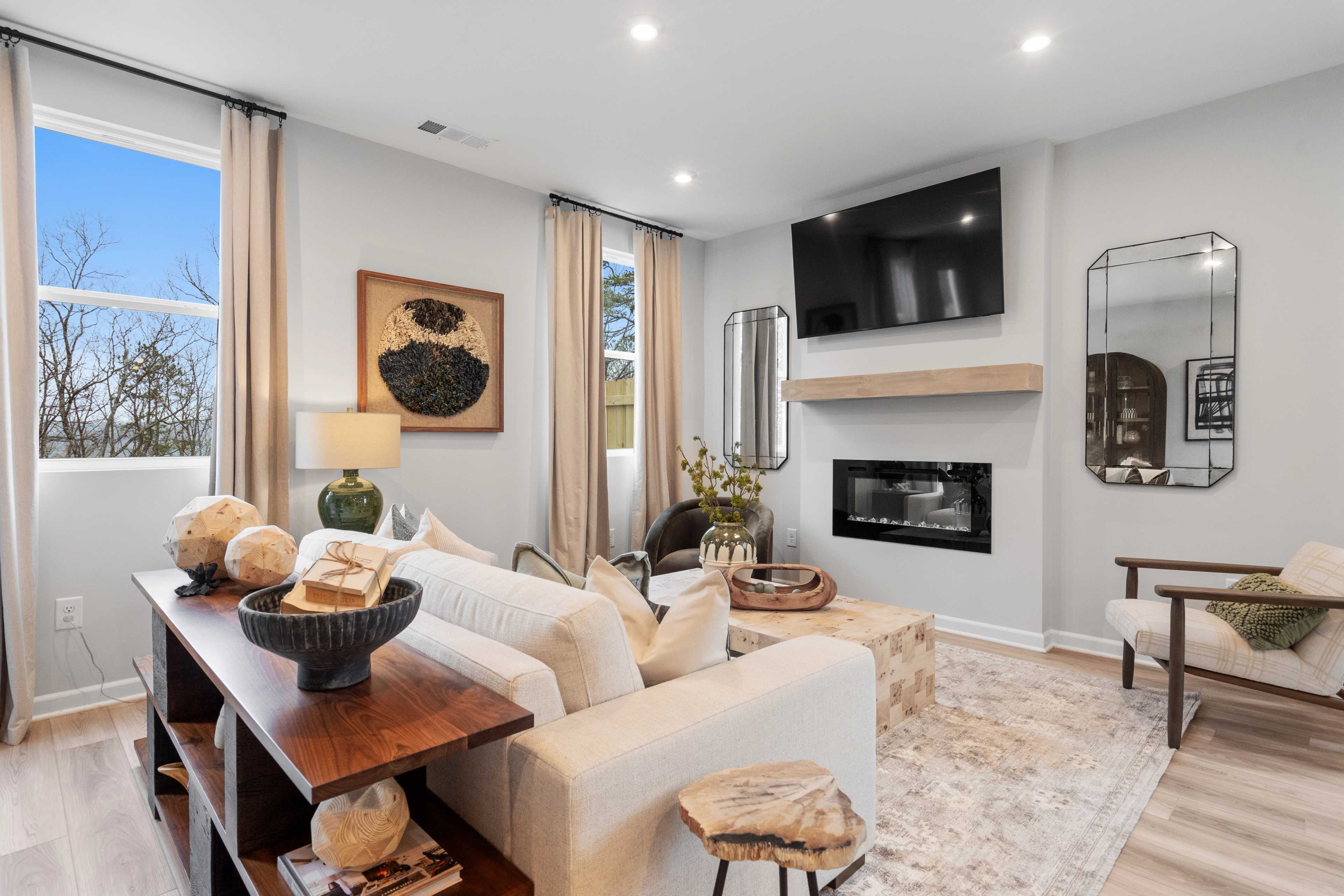 Cozy living room in Stegall Village Emerson Georgia with white sectional sofa gas fireplace mounted TV large windows and hardwood floors
