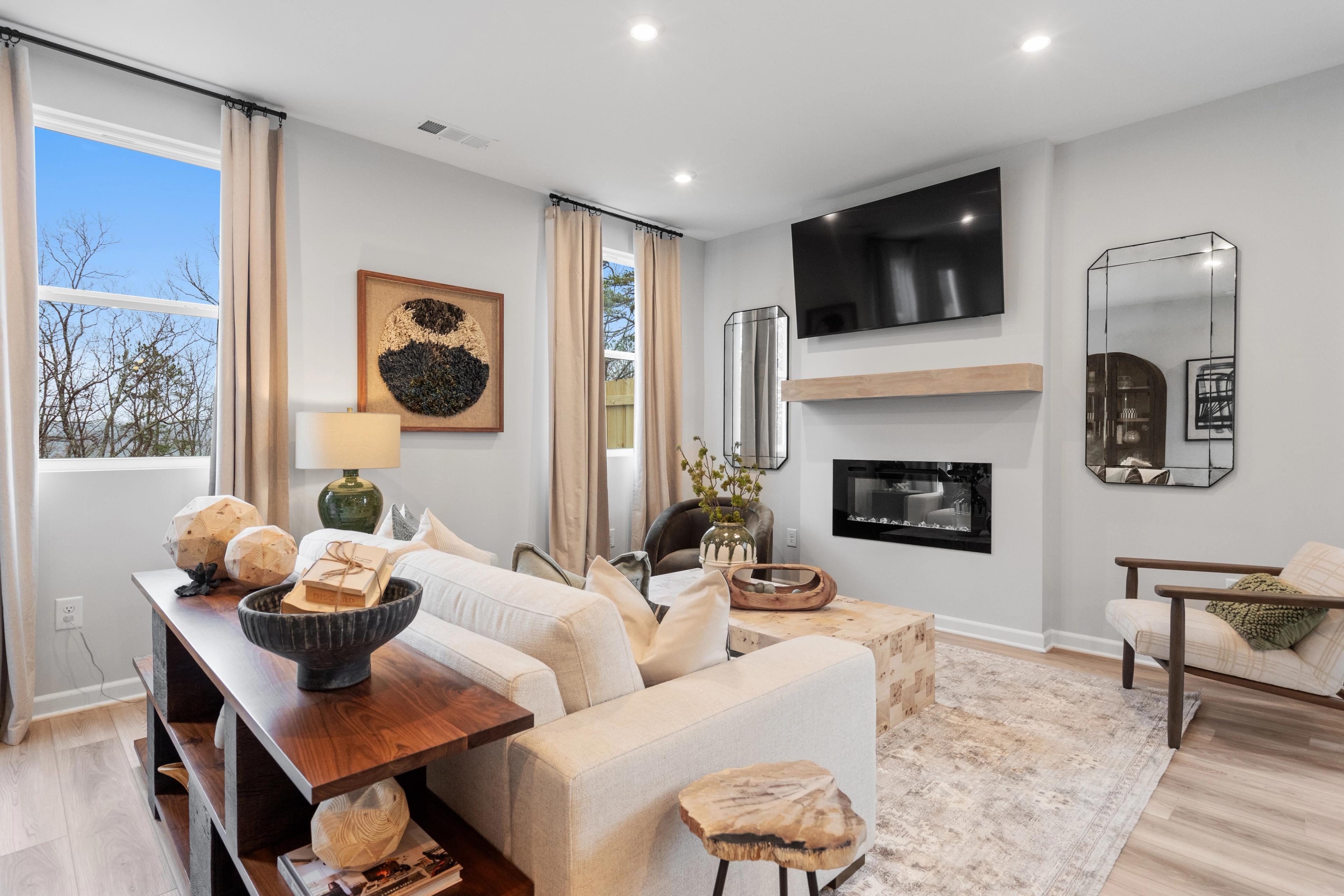 Cozy living room in Stegall Village Emerson Georgia with white sectional sofa gas fireplace mounted TV large windows and hardwood floors