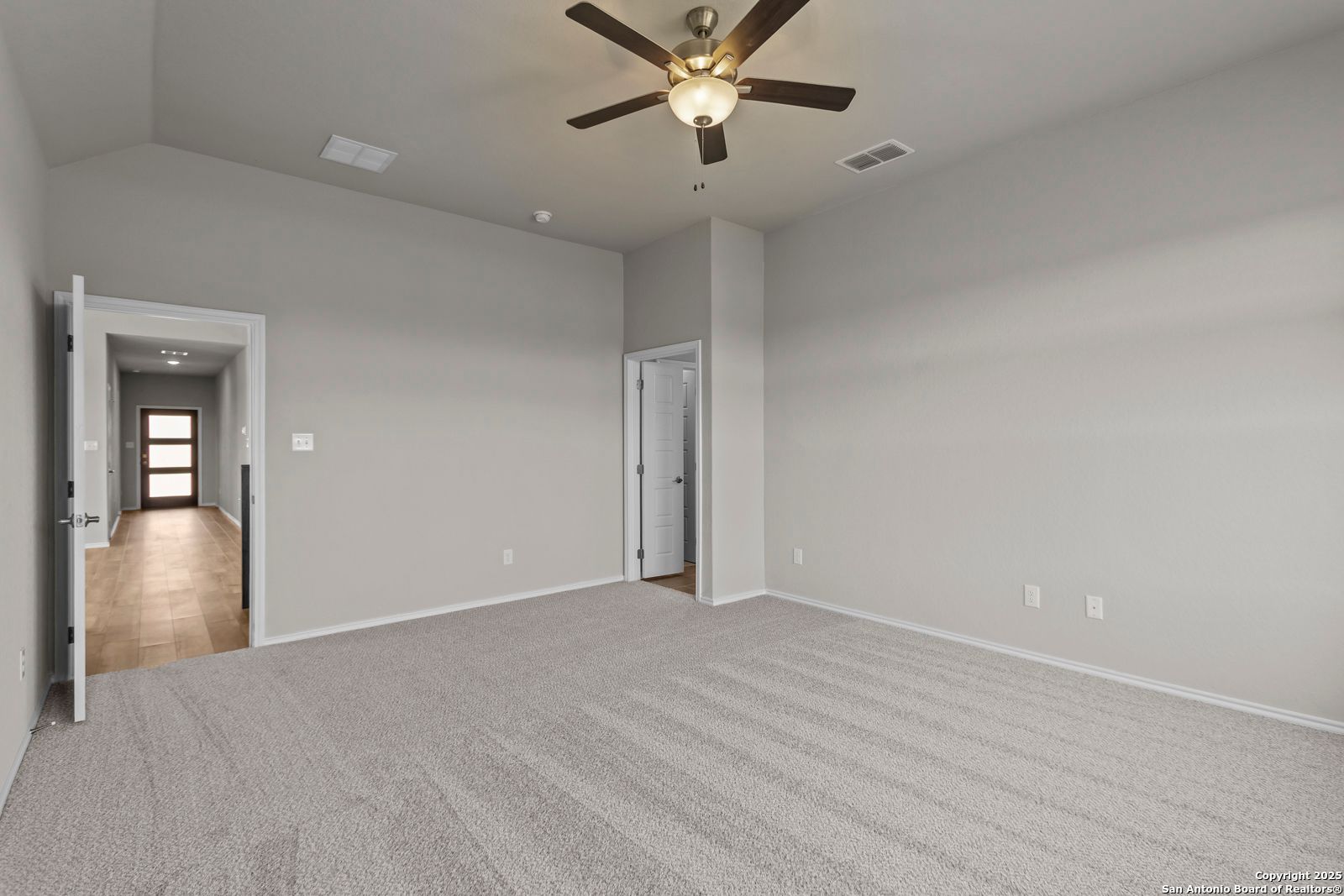 Spacious bedroom with vaulted ceiling, fan light, gray walls, and carpet in Davidson Homes Collin B, Seguin TX