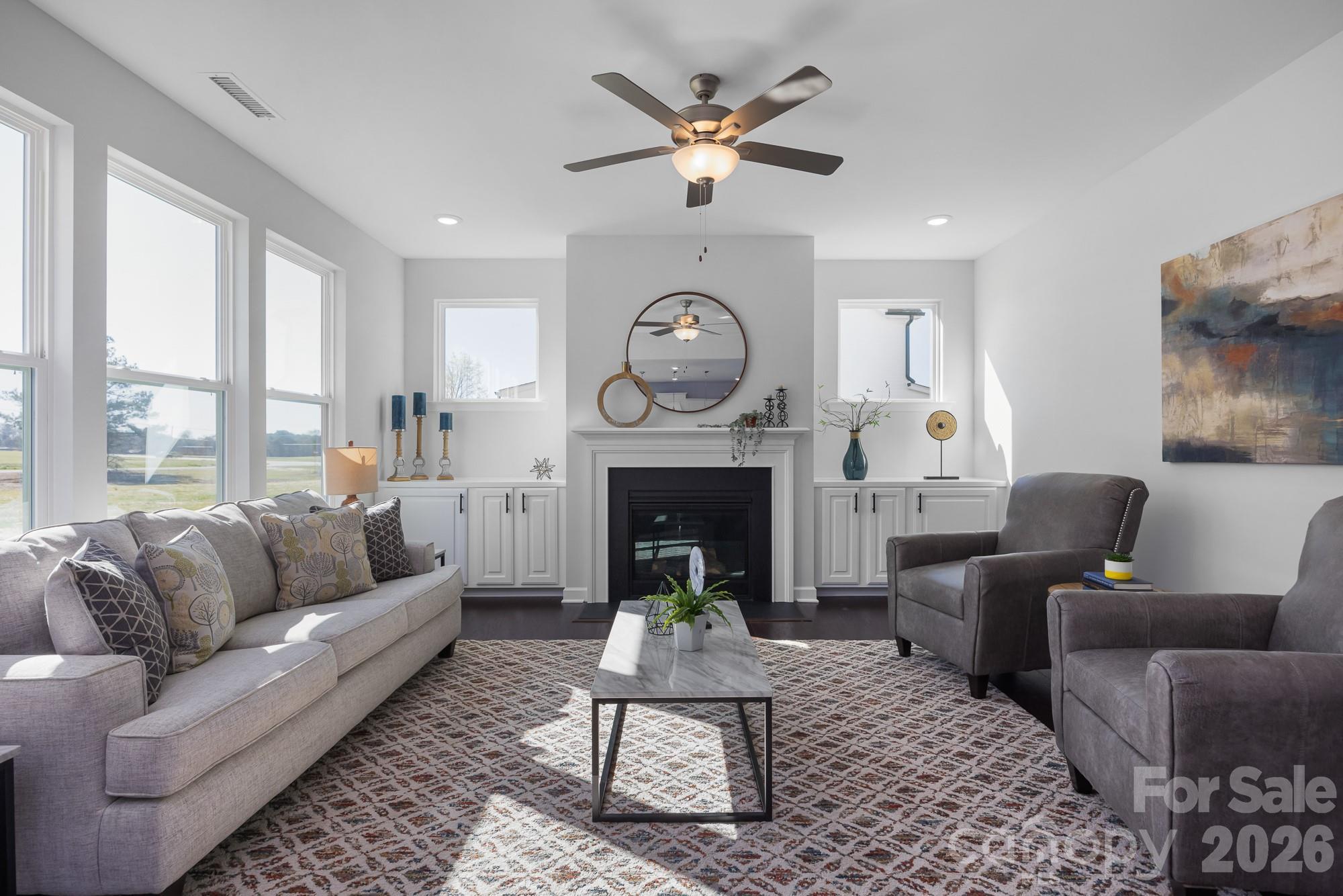Bright great room with fireplace, ceiling fan, and large windows in Davidson Homes The Hemlock D, Enclave at Belmont, North Carolina
