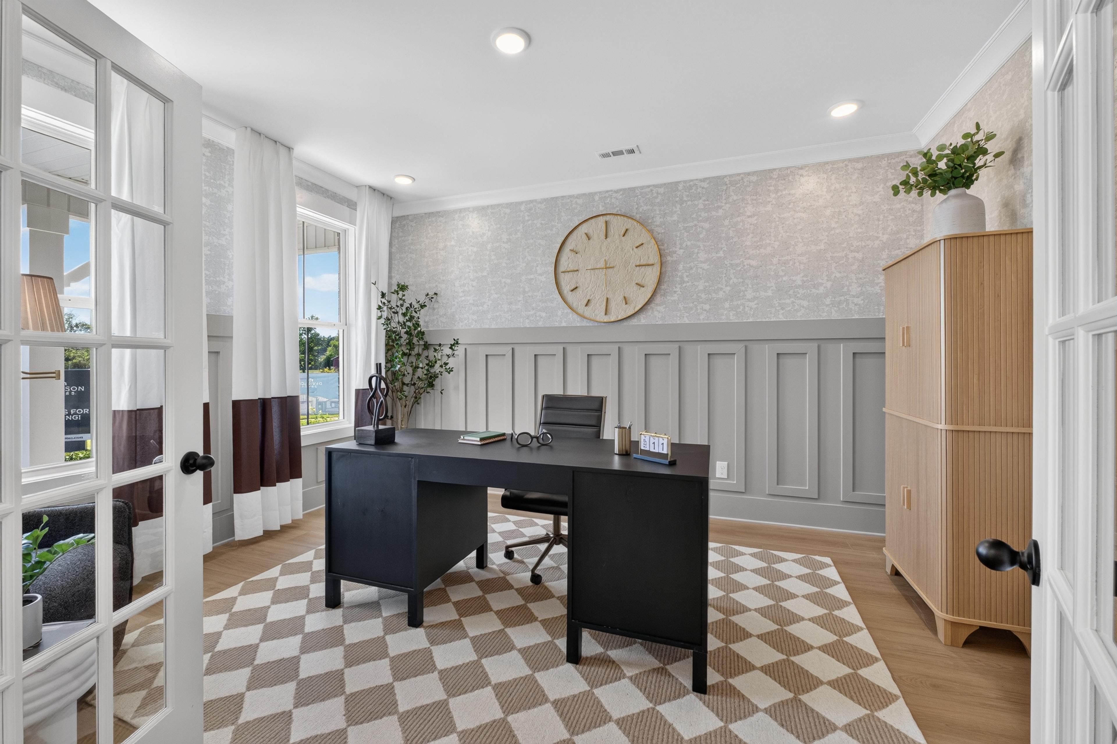 Stylish home office with black desk and wainscoting at Evergreen Mill by Davidson Homes in Madison, Alabama