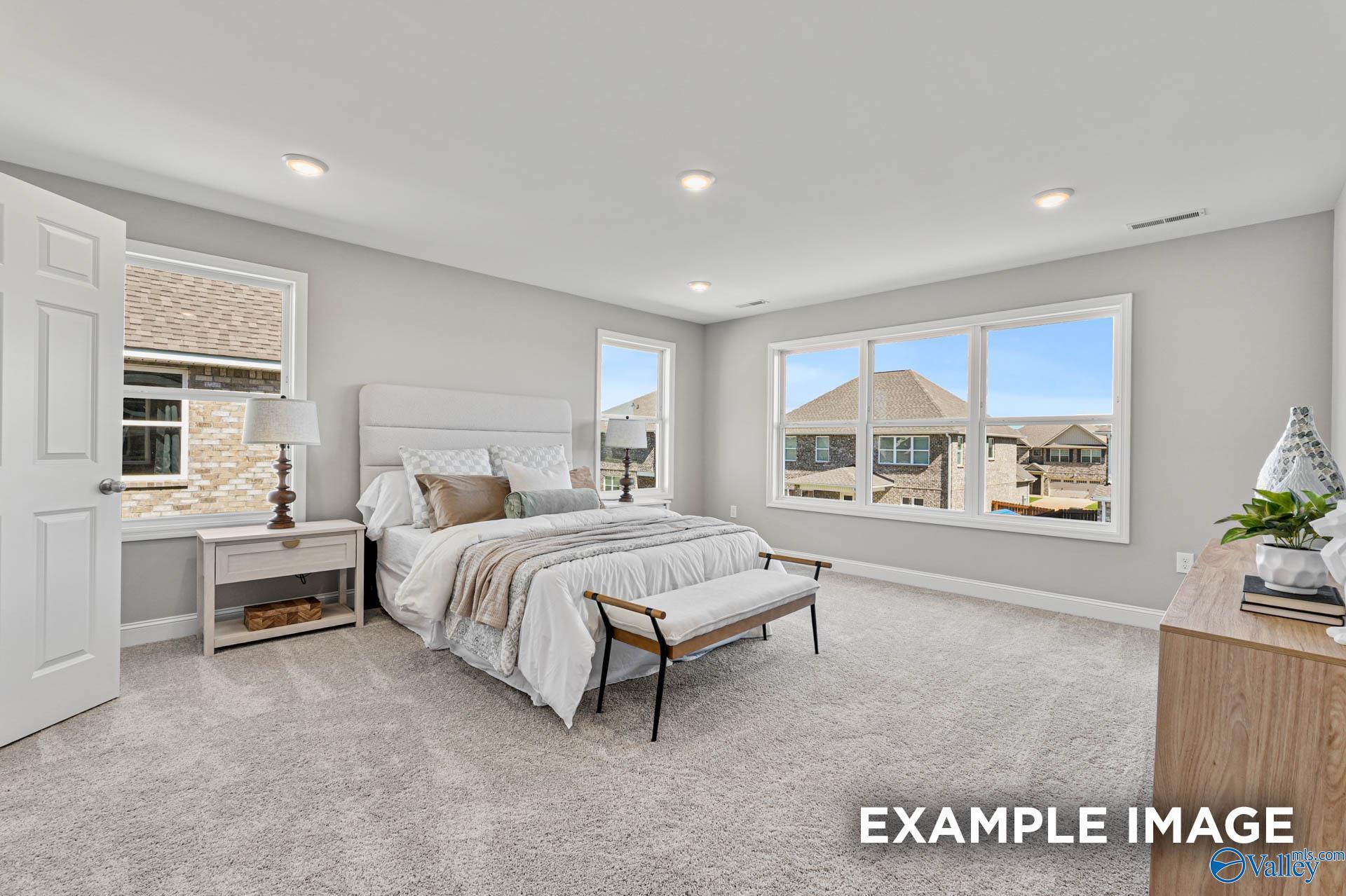 Bright master bedroom with upholstered bed, gray walls, large windows overlooking neighborhood in Davidson Homes Chelsea B, Toney AL