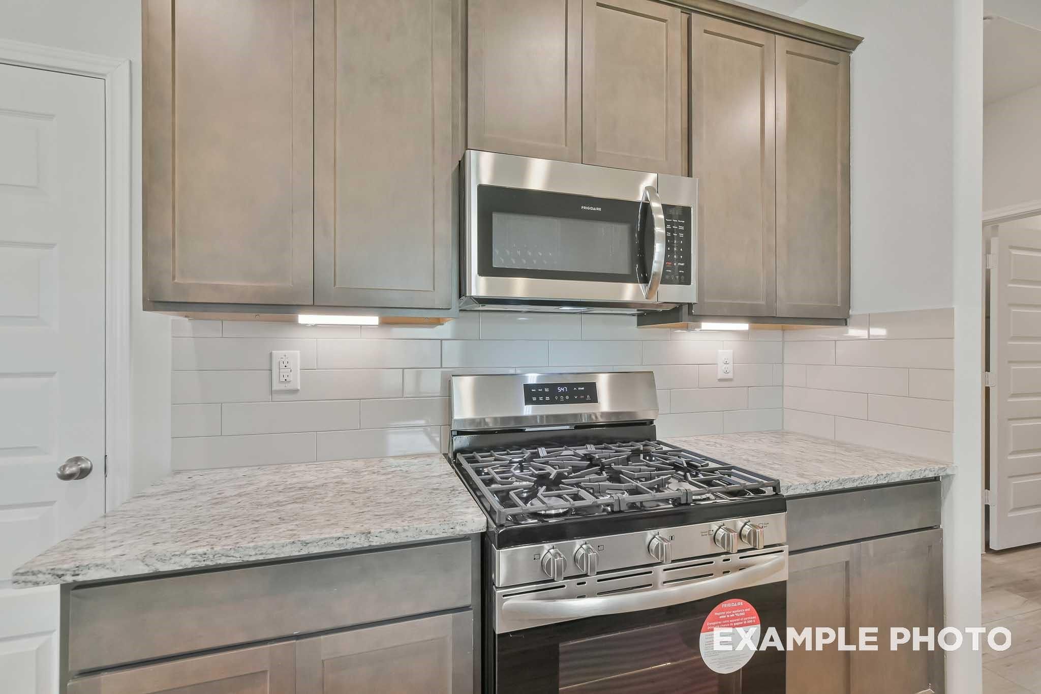 Modern kitchen with granite countertops, subway tile backsplash, shaker cabinets, and stainless appliances in The Frio F, Conroe, Texas