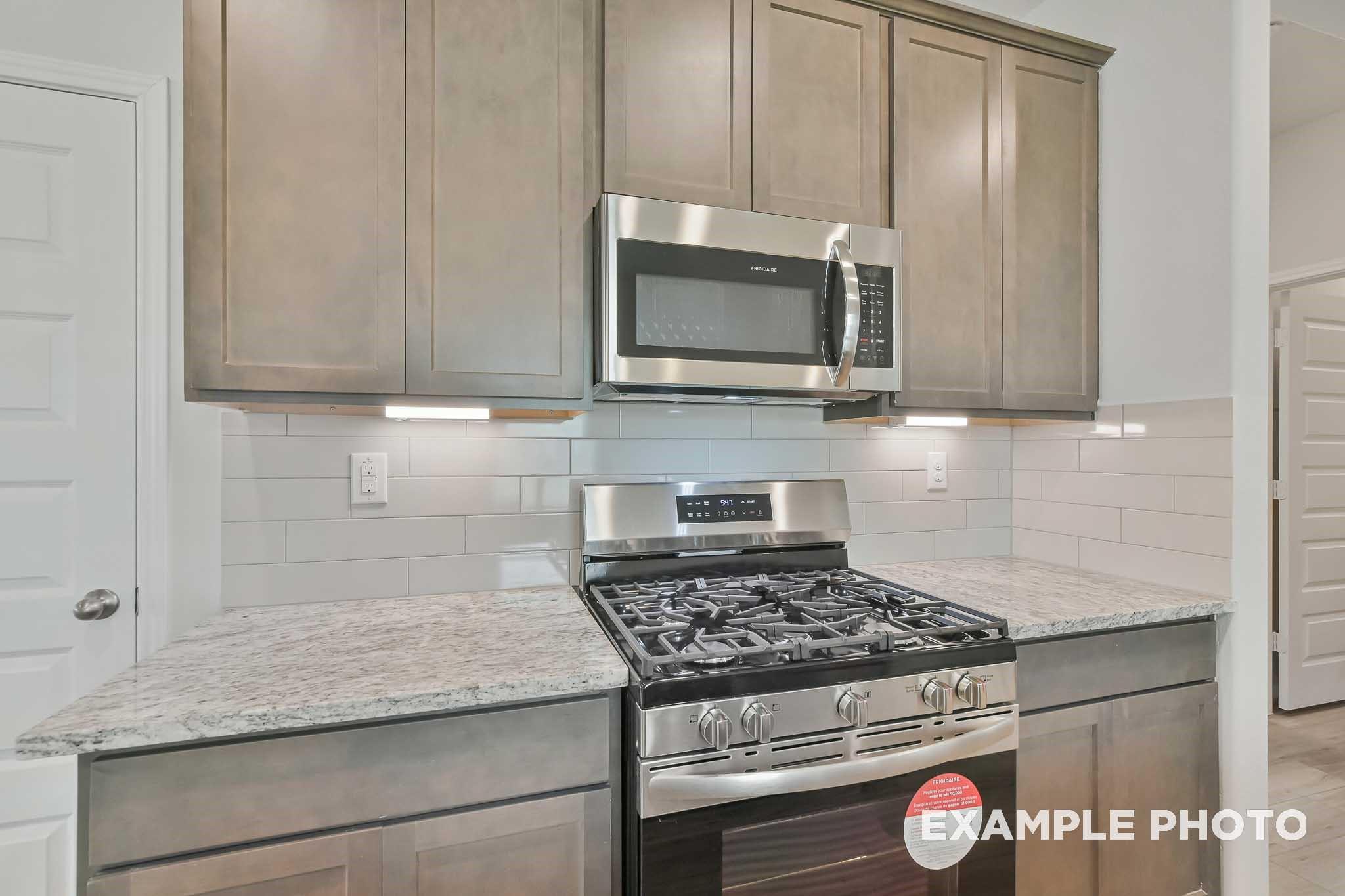 Modern kitchen with granite countertops, subway tile backsplash, shaker cabinets, and stainless appliances in The Frio F, Conroe, Texas