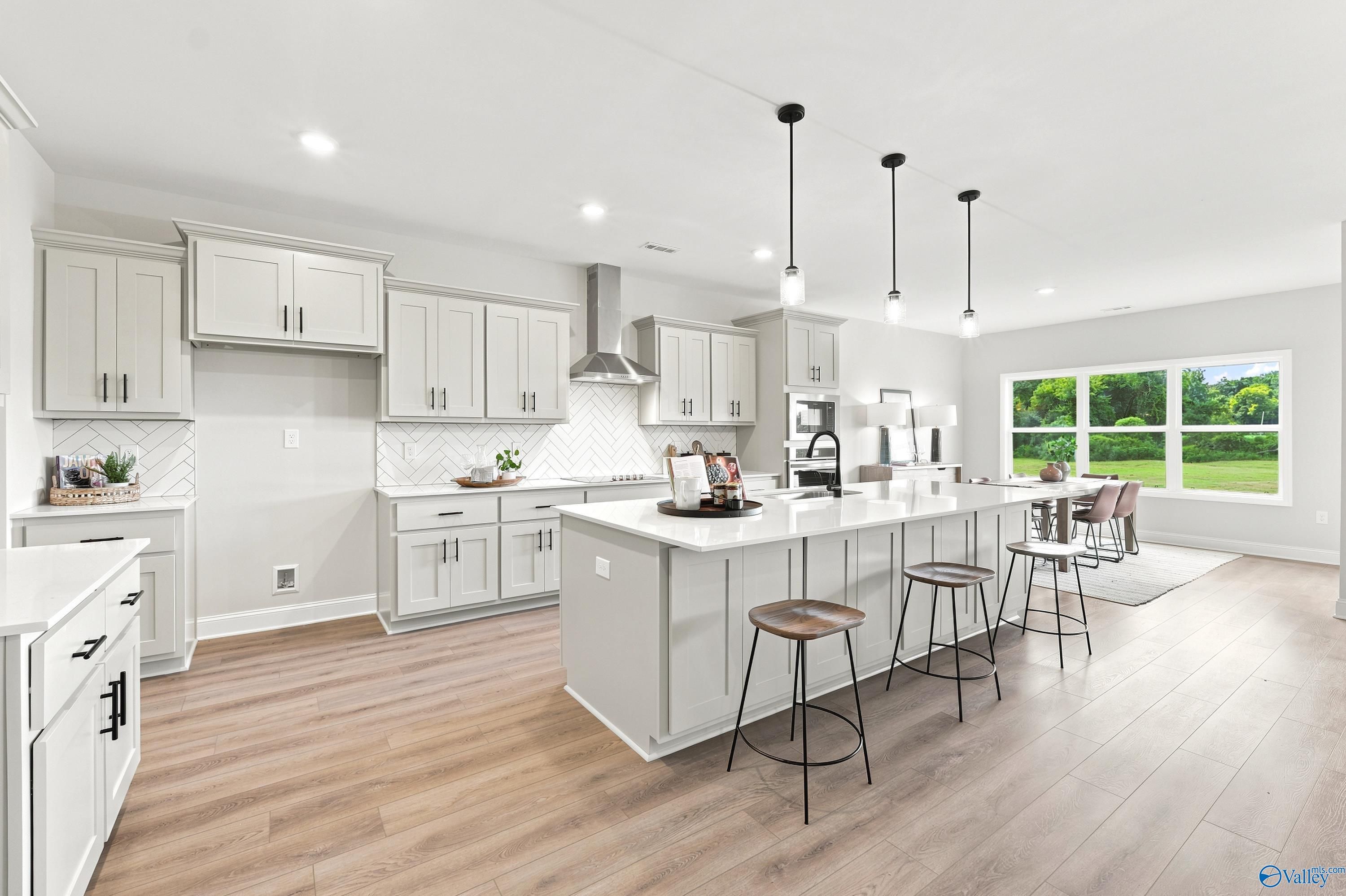 Modern kitchen with large island, white cabinets, and herringbone backsplash in The Finleigh home at Riverton Preserve.