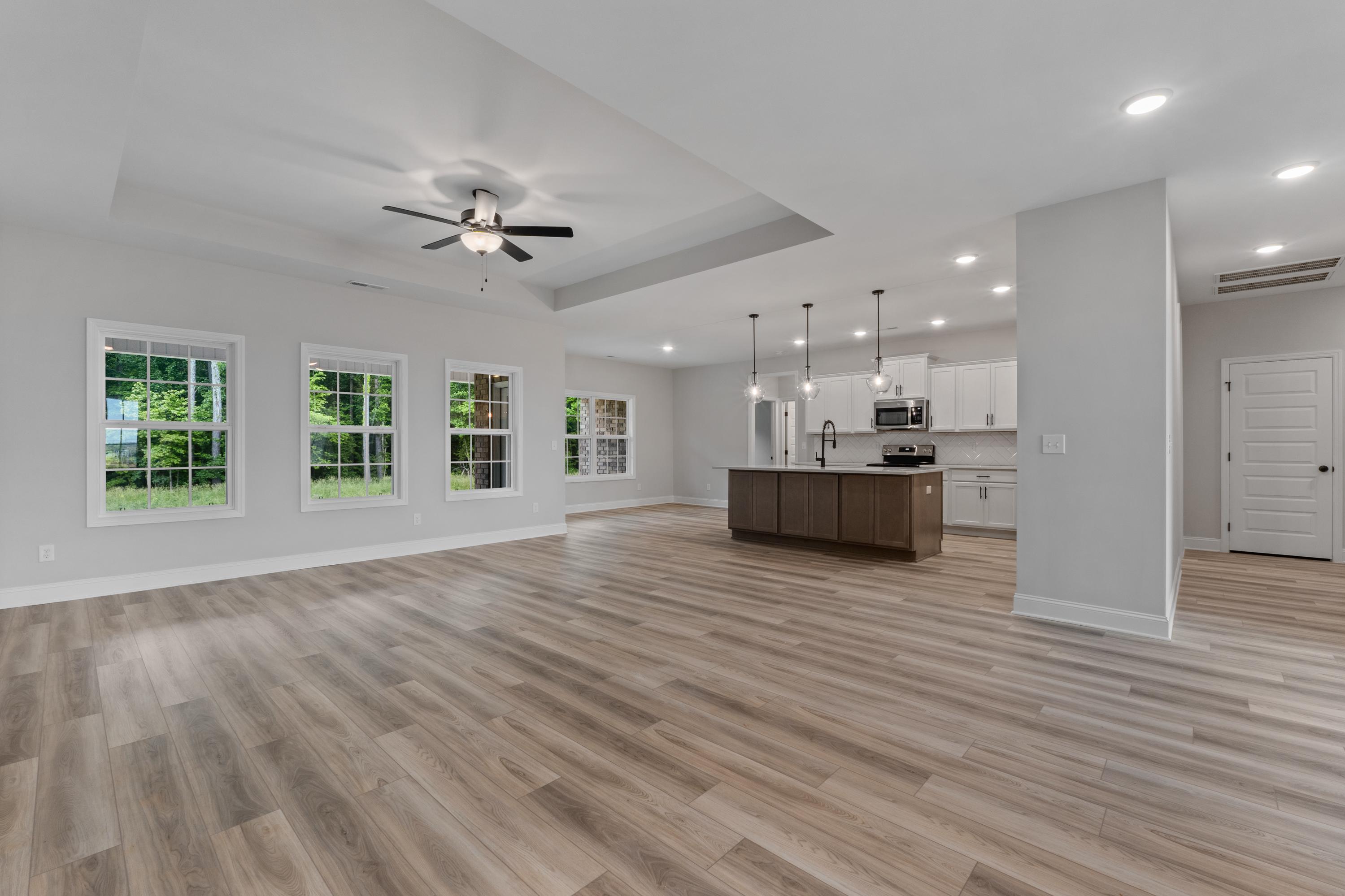 Spacious open-concept kitchen and living area in The Oxford with large island, hardwood floors, and large windows