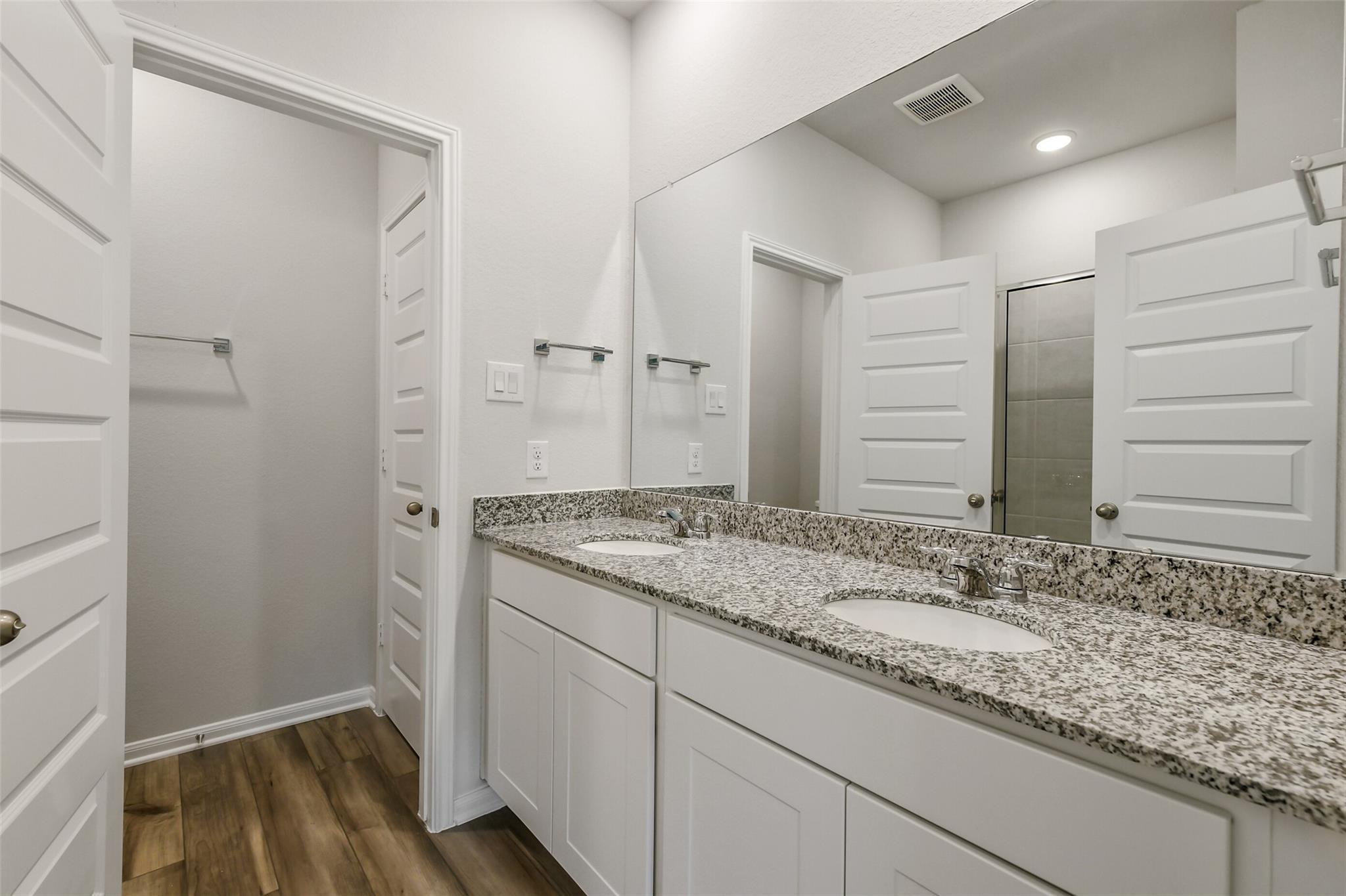 Modern master bathroom featuring double vanity with granite countertops and mirrors in Davidson Homes The Sabine E, Conroe, Texas