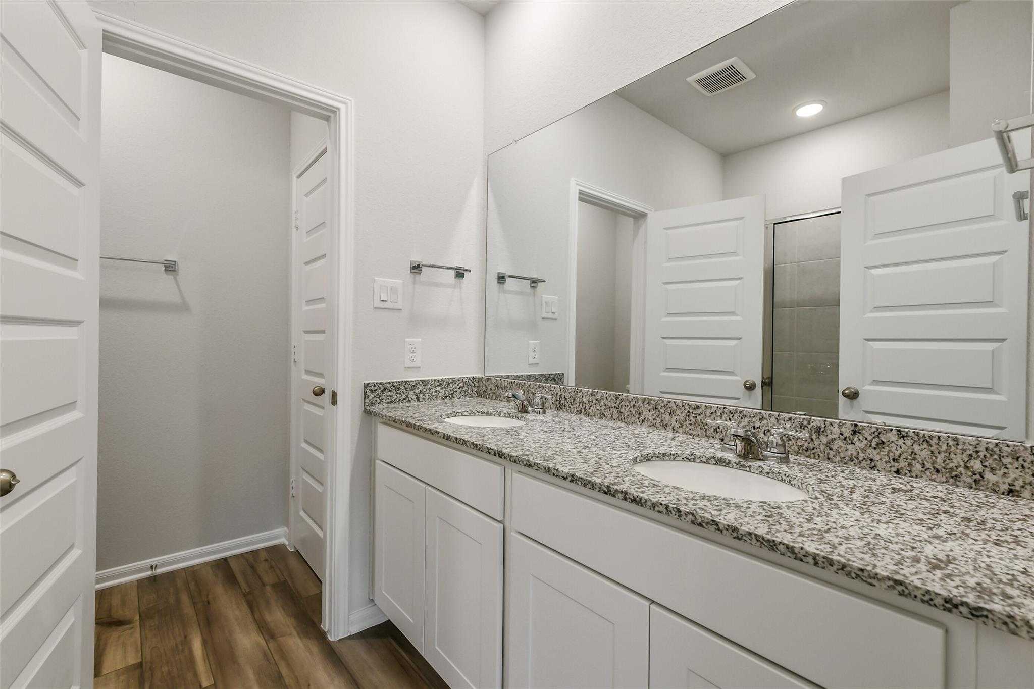 Modern master bathroom featuring double vanity with granite countertops and mirrors in Davidson Homes The Sabine E, Conroe, Texas