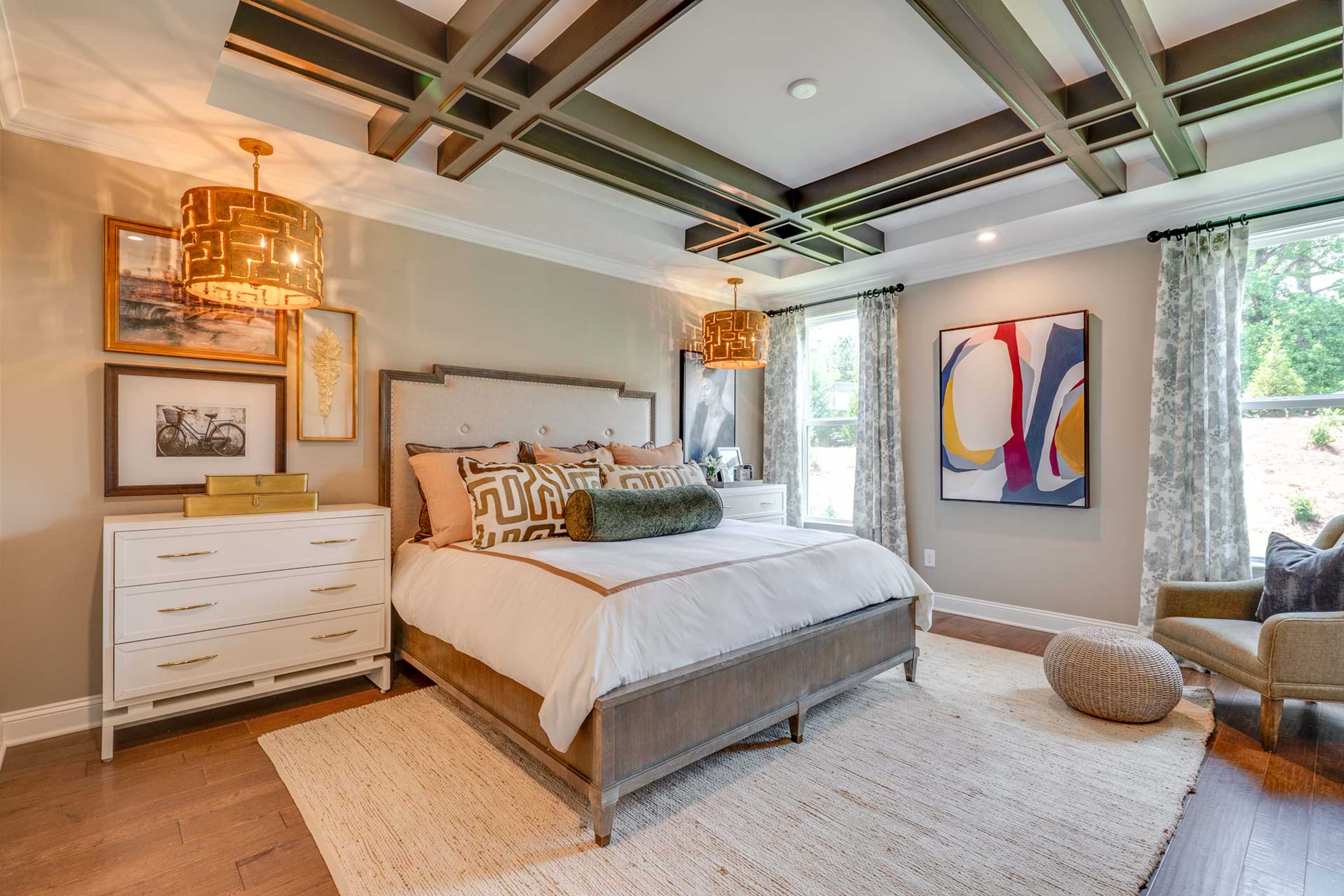 Luxurious master bedroom at Hasentree in Wake Forest NC by Davidson Homes with king bed, beamed ceiling, and rattan pendant lights