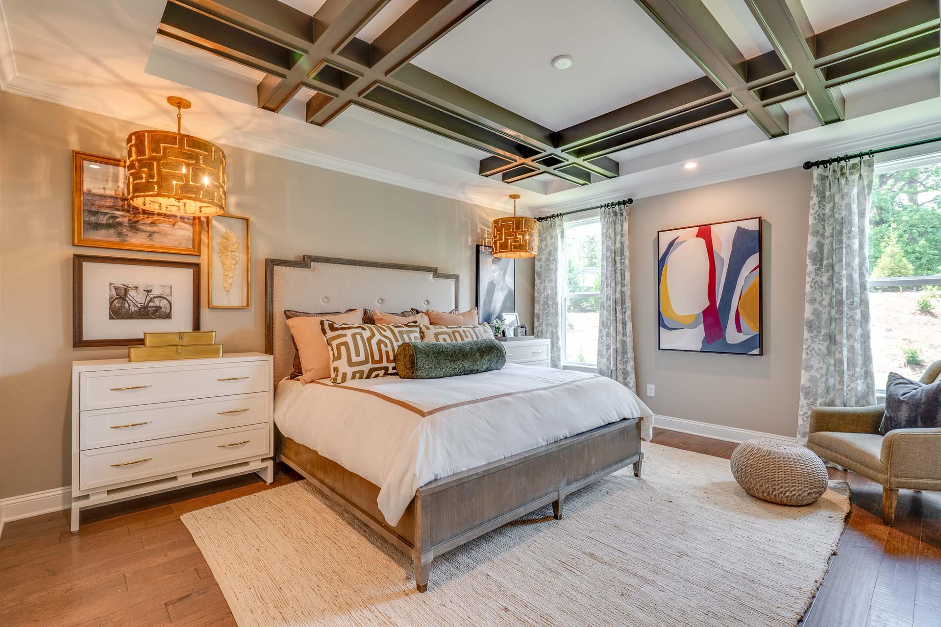 Luxurious master bedroom at Hasentree in Wake Forest NC by Davidson Homes with king bed, beamed ceiling, and rattan pendant lights