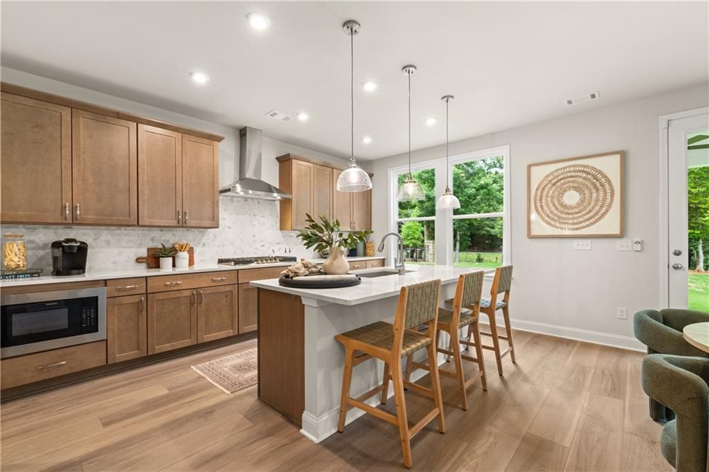 Modern kitchen with wood cabinets, white island, pendant lights, and bar seating in Davidson Homes The Danbury E, Buford, Georgia