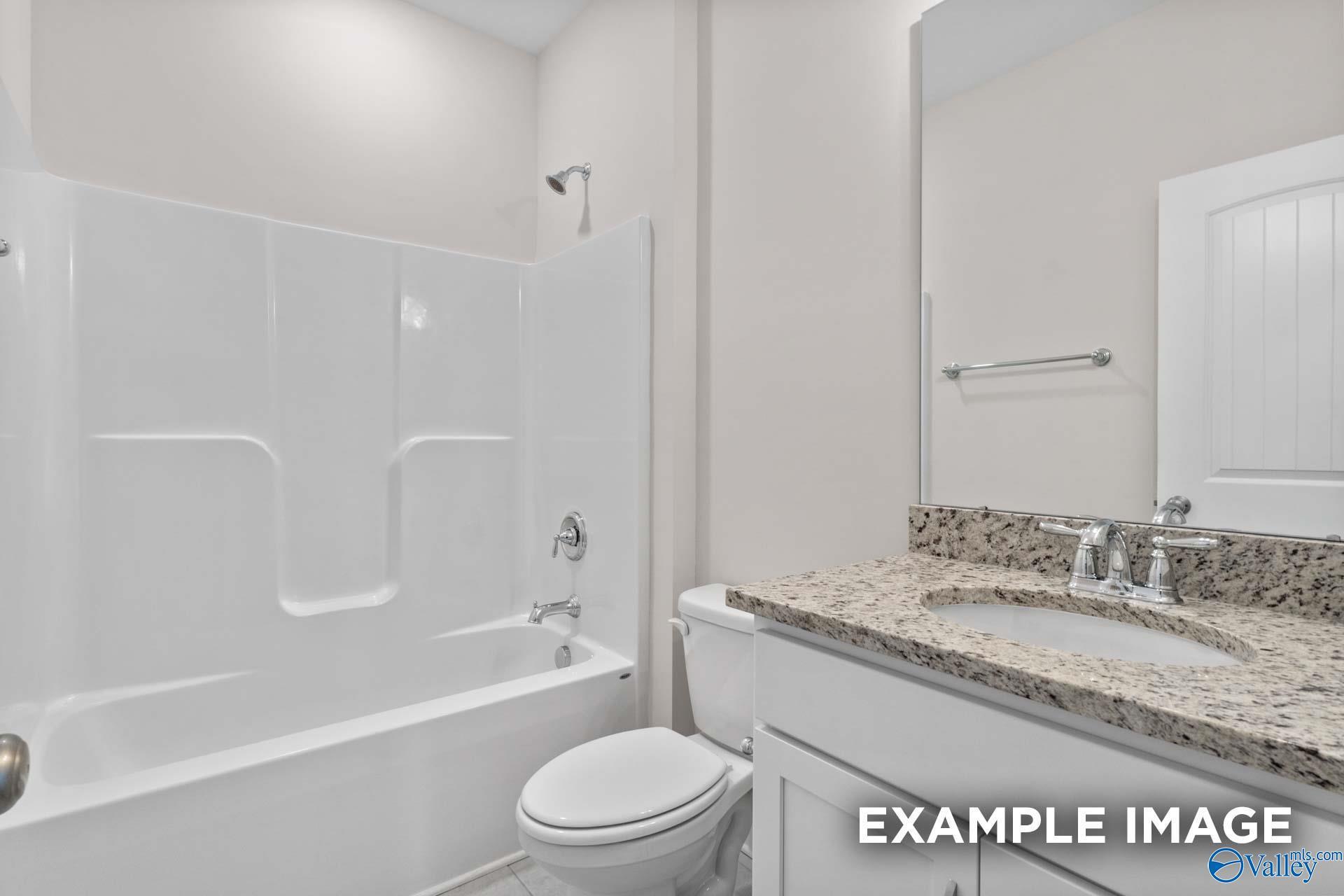 Modern bathroom featuring granite vanity, white tub-shower combo, and toilet in The Montgomery C by Davidson Homes, Harvest, Alabama