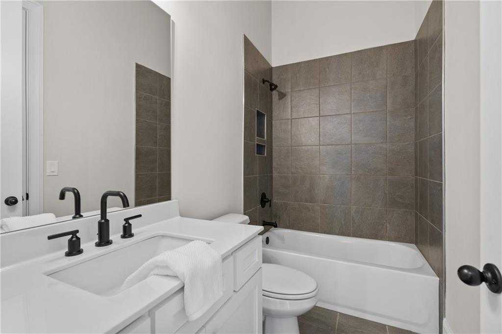 Modern bathroom with soaking tub, brown tiled shower, white vanity, black faucets in Davidson Homes The Seaside B, Woodstock, GA