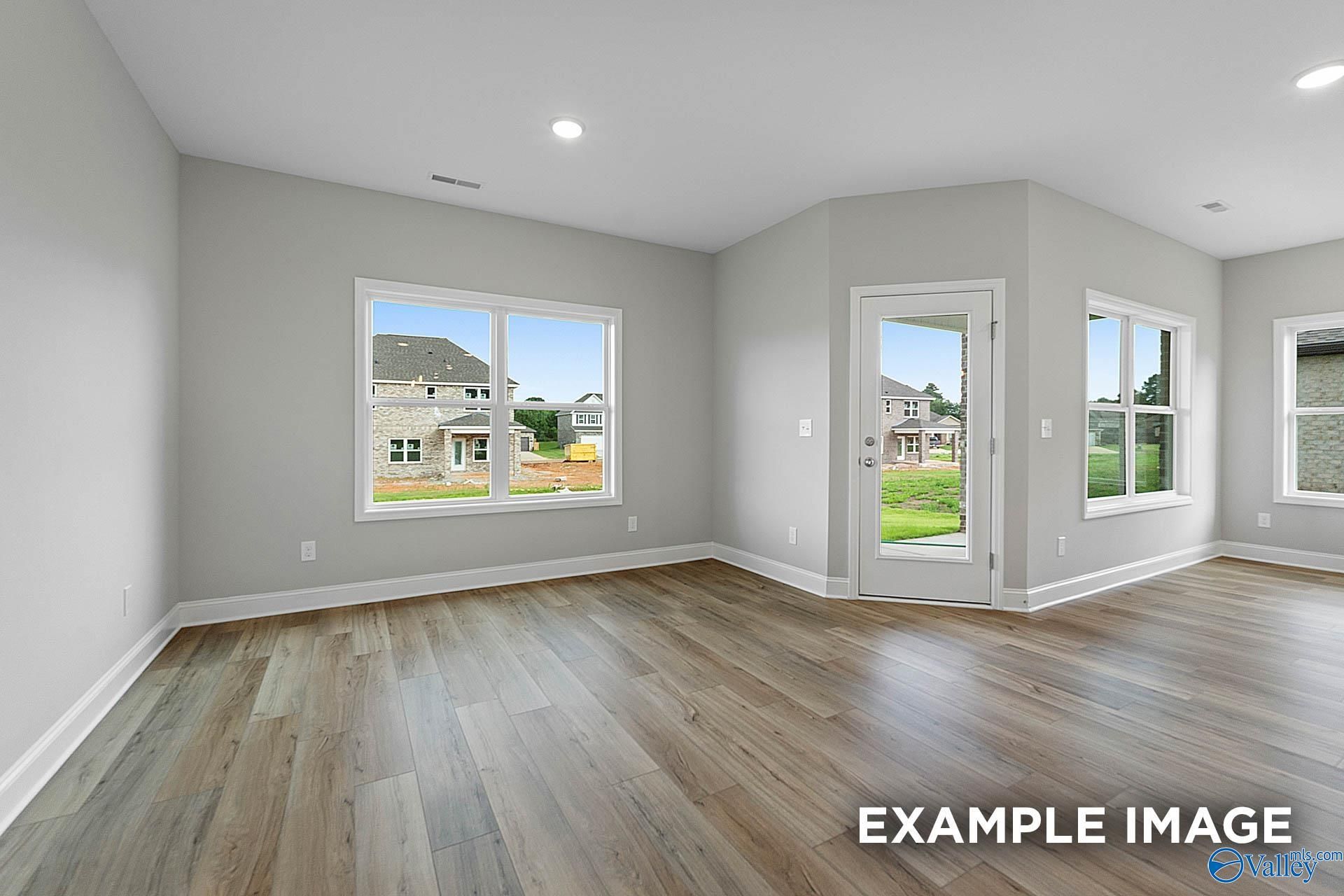 Bright living room with large windows, French doors to lush backyard, hardwood floors in Davidson Homes The Franklin E, Hazel Green, AL