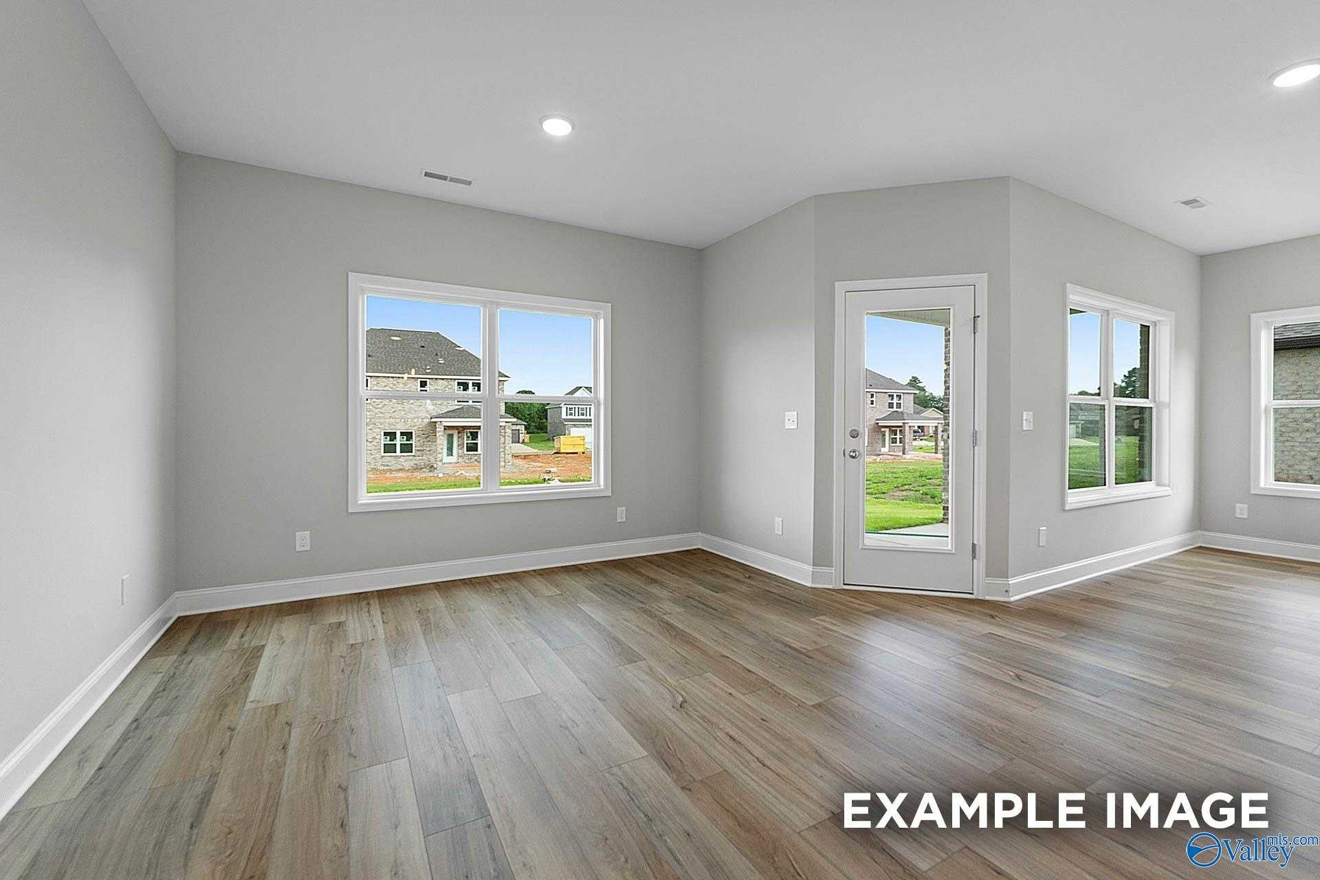 Bright living room with large windows, French doors to lush backyard, hardwood floors in Davidson Homes The Franklin E, Hazel Green, AL