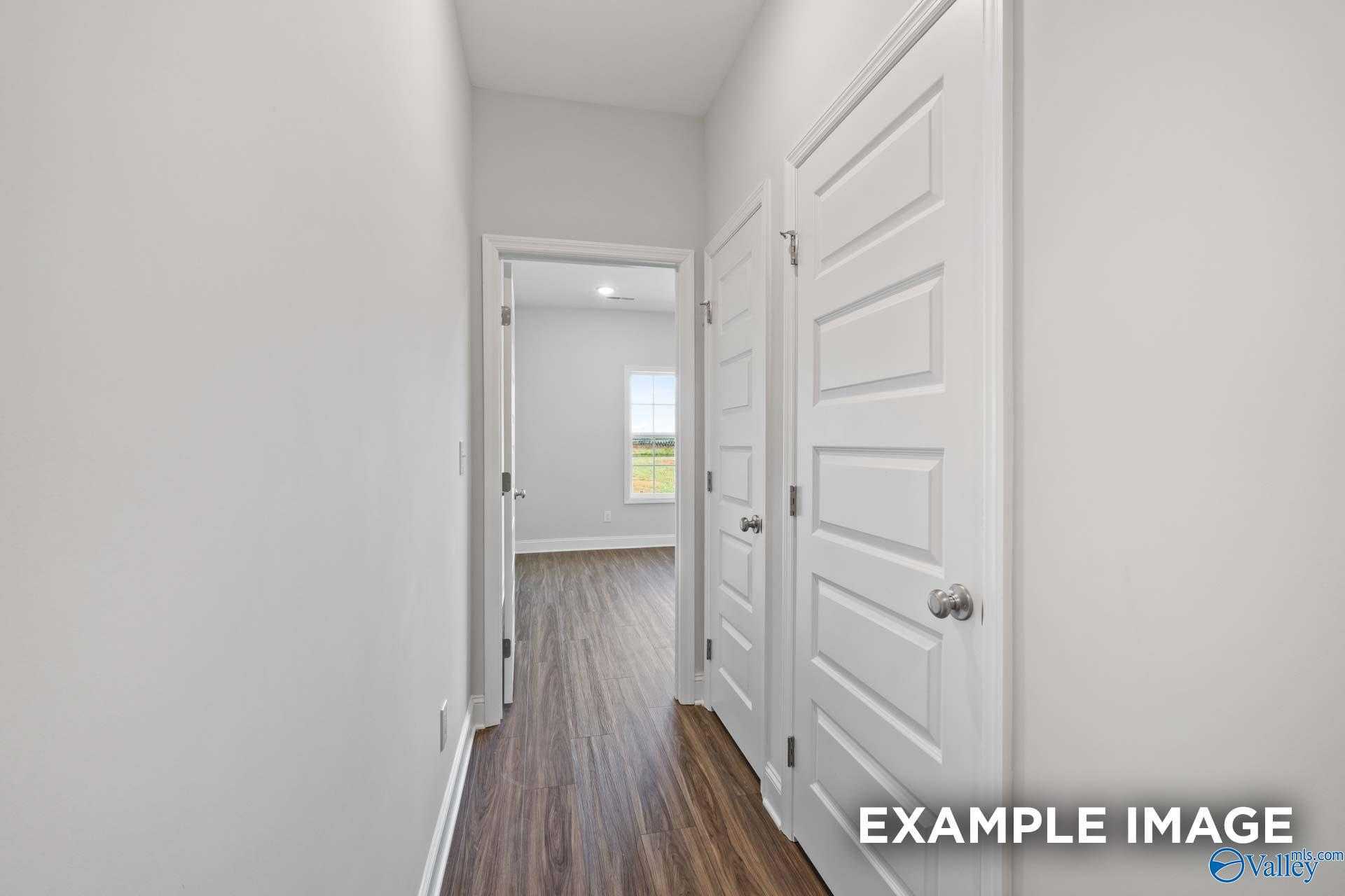 Bright hallway with white doors, hardwood floors, and window view in The Montgomery 3-bedroom home, Davidson Homes, Athens, Alabama