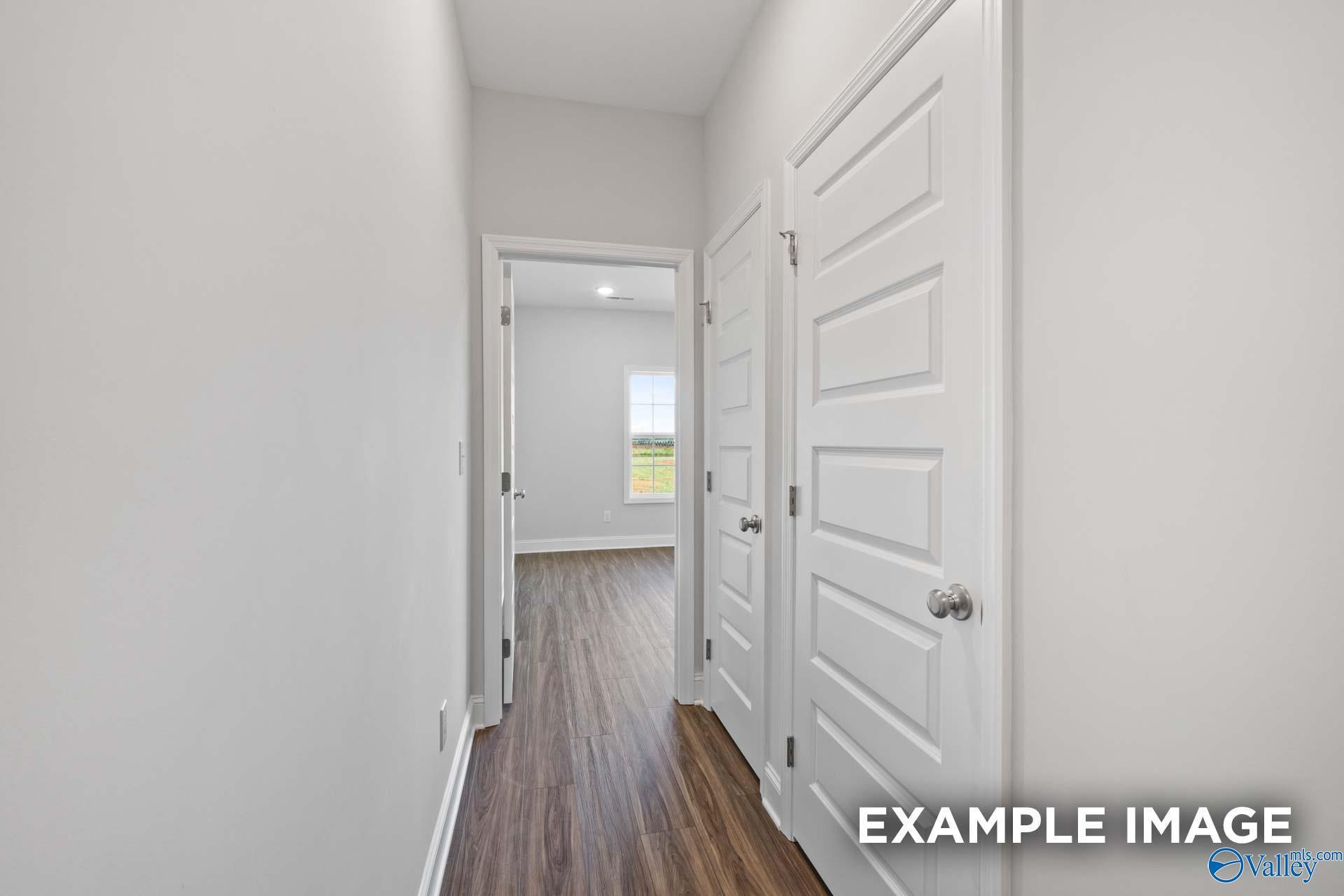 Bright hallway with white doors, hardwood floors, and window view in The Montgomery 3-bedroom home, Davidson Homes, Athens, Alabama