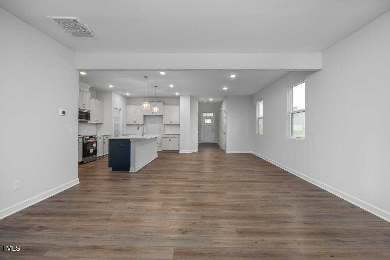 Modern open-concept kitchen with white cabinets, navy island, and stainless appliances in The Adalynn B 4-bedroom home, Lillington, NC