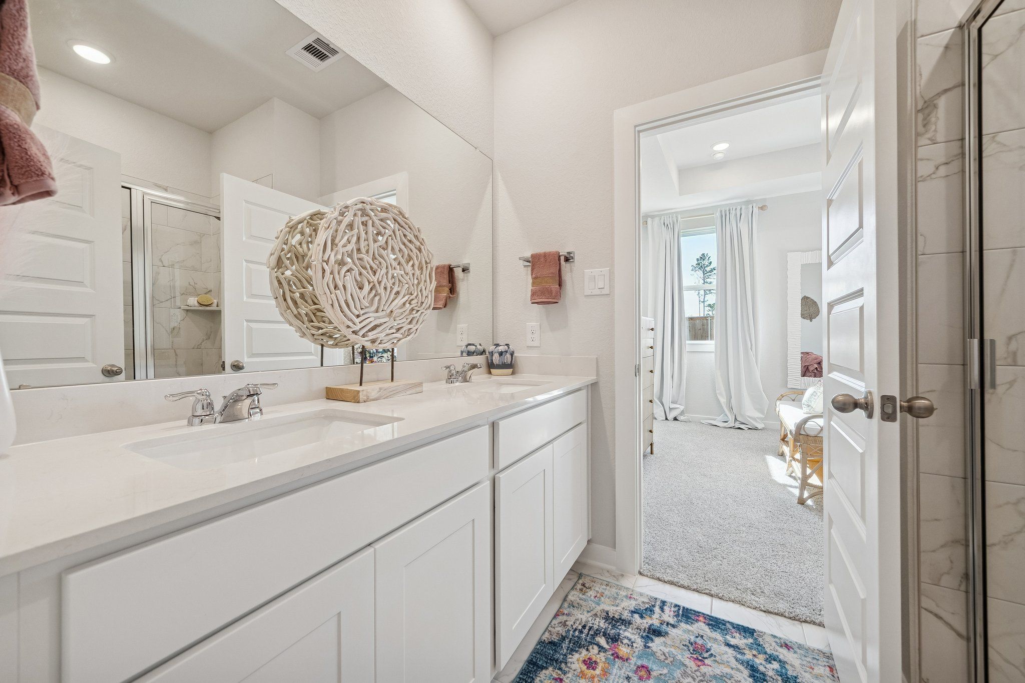 Bright primary bathroom at Spring Branch Crossing in Conroe Texas featuring double white vanity, quartz counters and walk-in shower