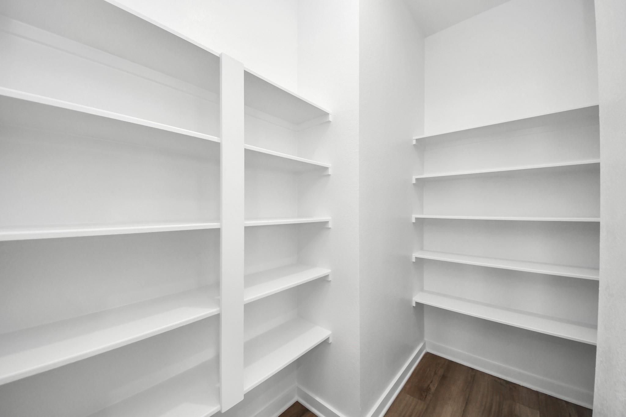 Walk-in pantry with white built-in shelving in The Riviera C floor plan at River Ranch Meadows, Dayton, Texas.