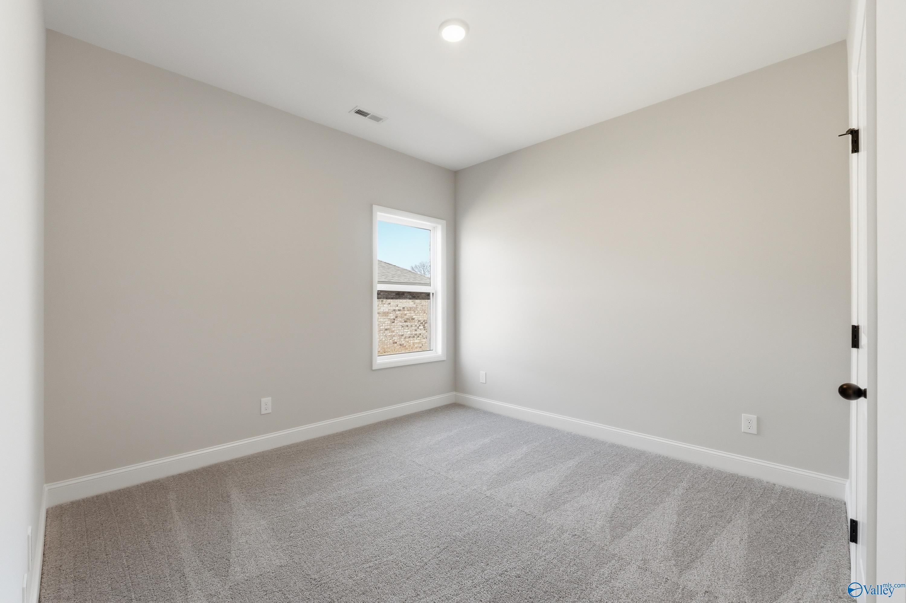 Cozy bedroom with beige walls, large window, and plush carpet in Davidson Homes The Franklin C, New Market, Alabama