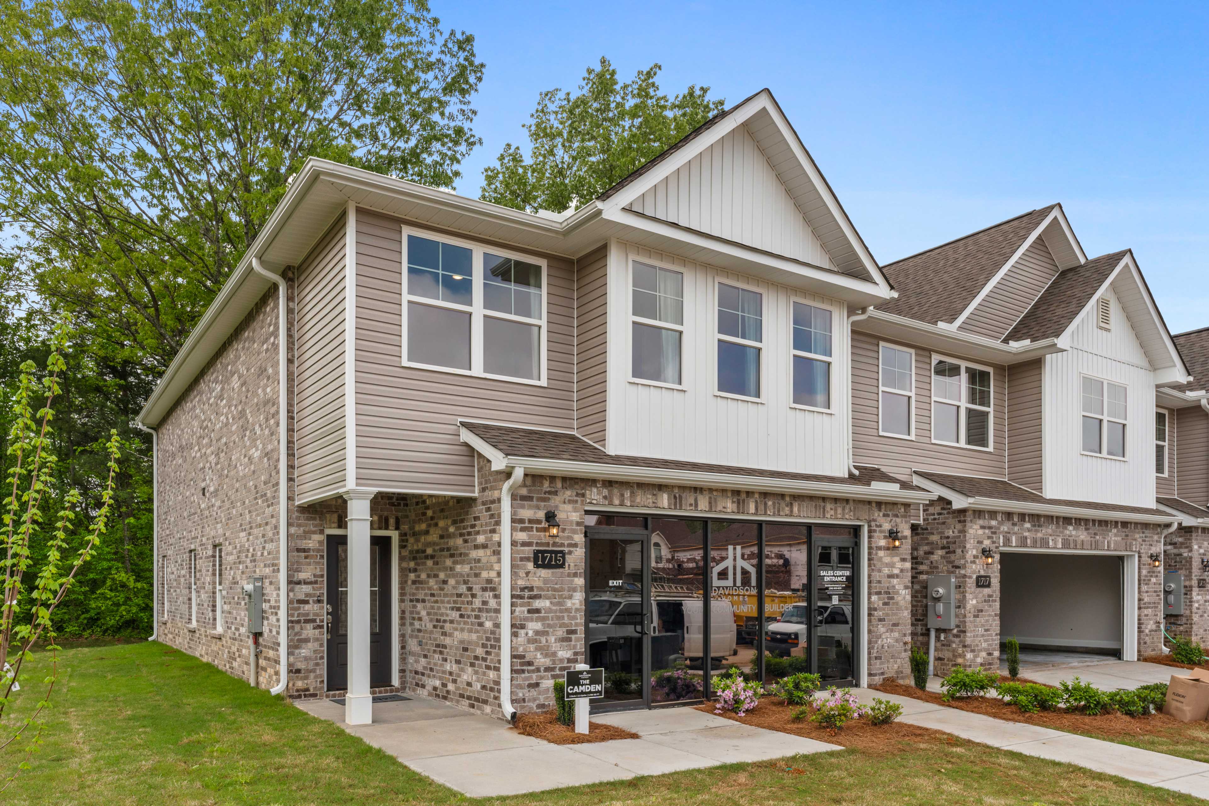 Modern two-story townhomes at Pavilion in Huntsville Alabama with beige brick facades covered porches attached garages and lush landscaping