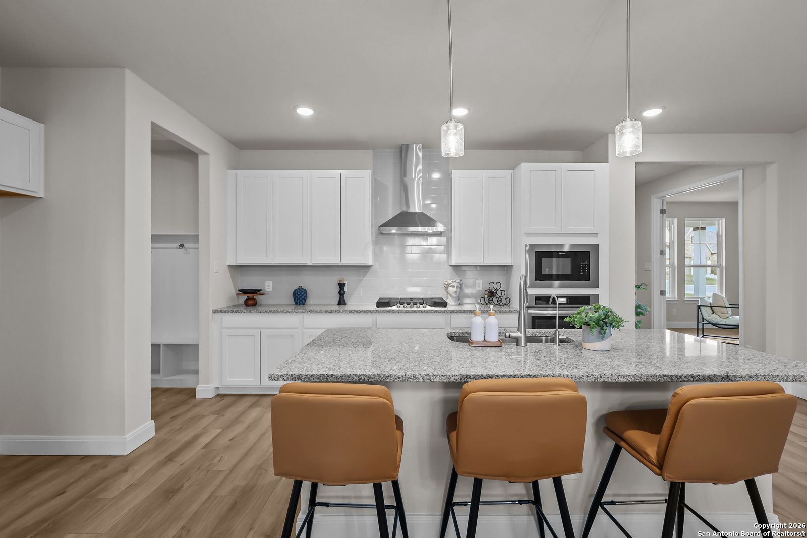 Modern white kitchen with granite island, stainless steel appliances, pendant lights in The Lanier H floor plan, Ladera San Antonio