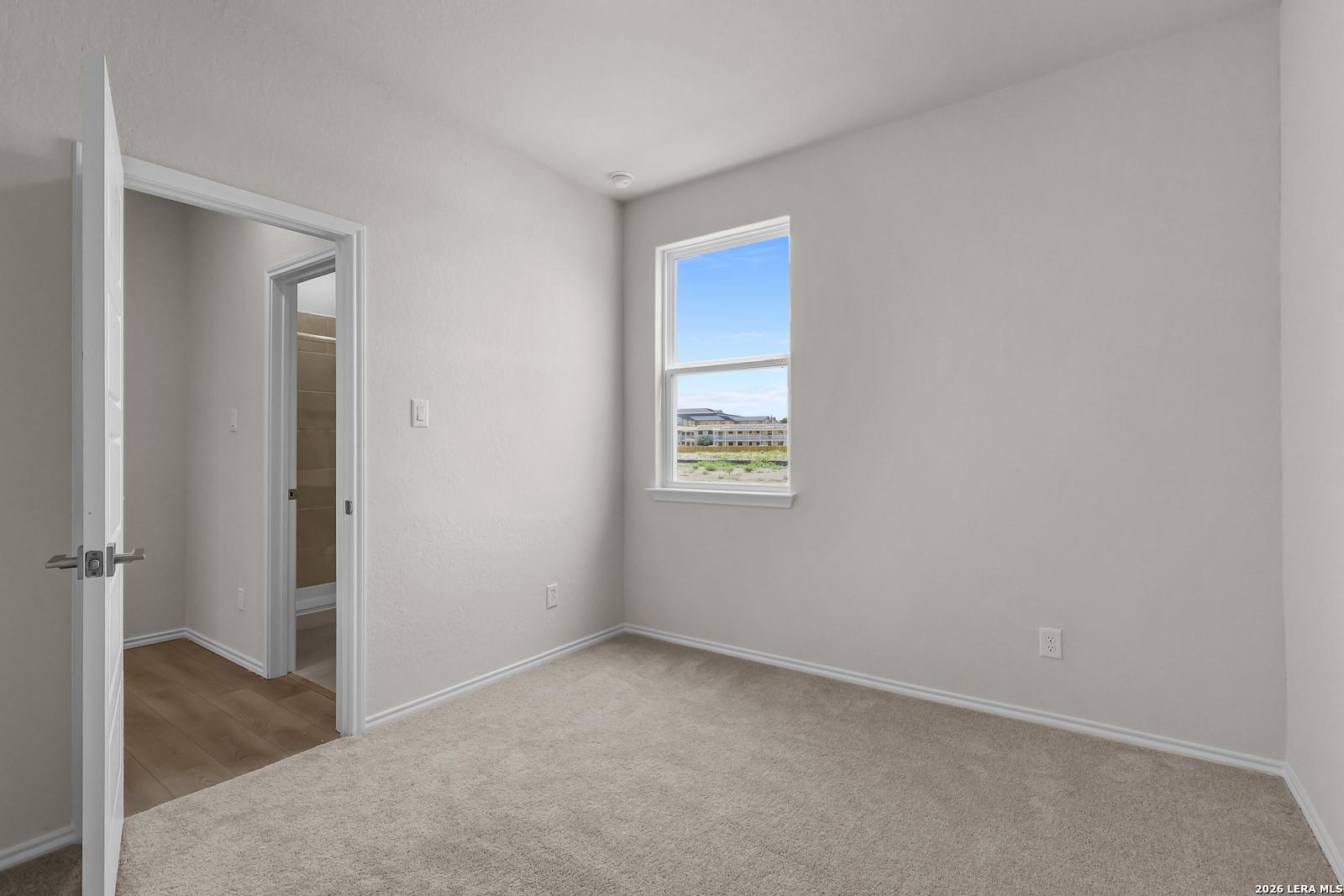 Bright bedroom with soft carpeting and attached bathroom in The San Marcos F floor plan at Rayburn Valley, San Antonio.