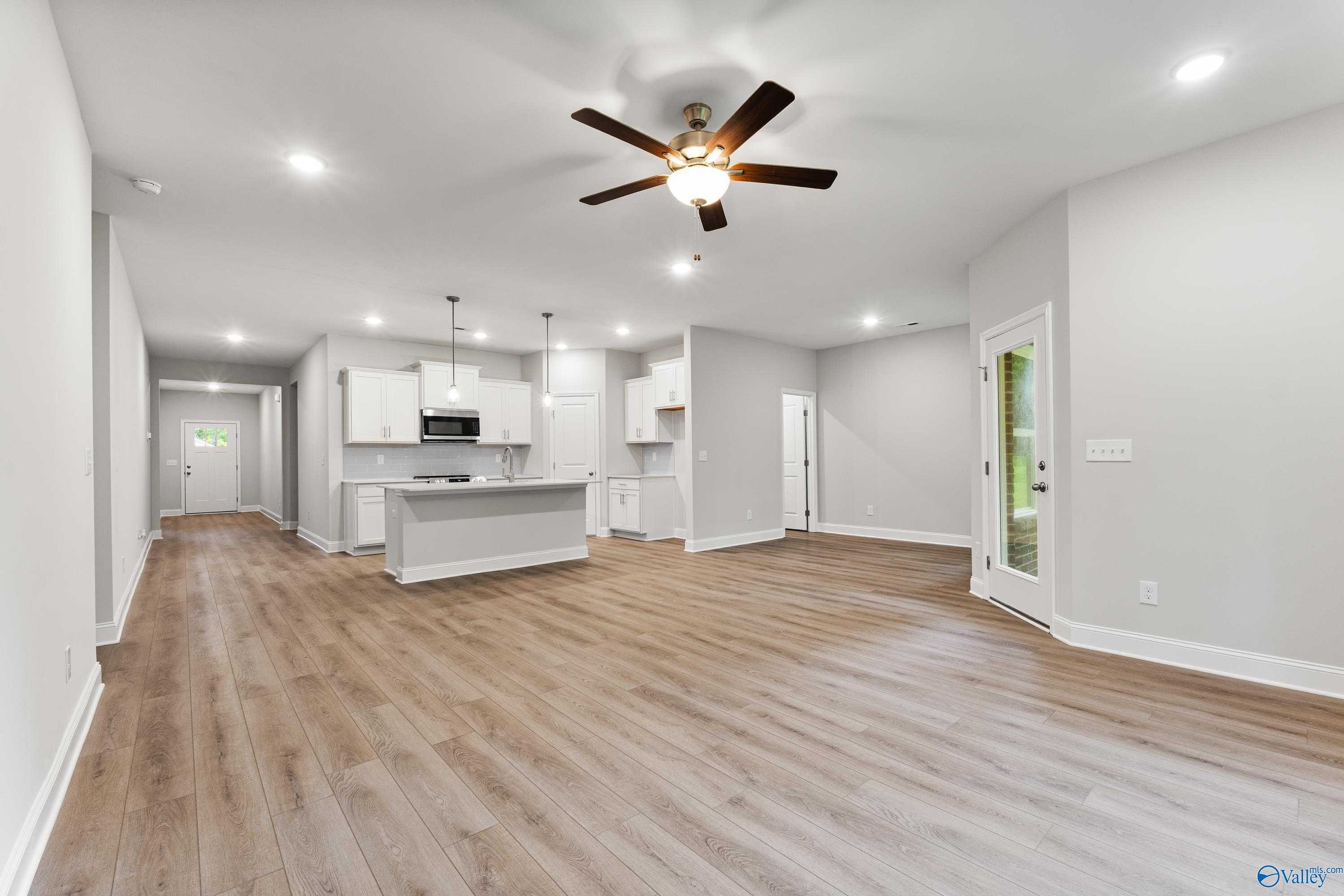 Open-concept kitchen with white cabinets, island, and ceiling fan in The Daphne 4-bedroom home, Spragins Cove, Huntsville, Alabama