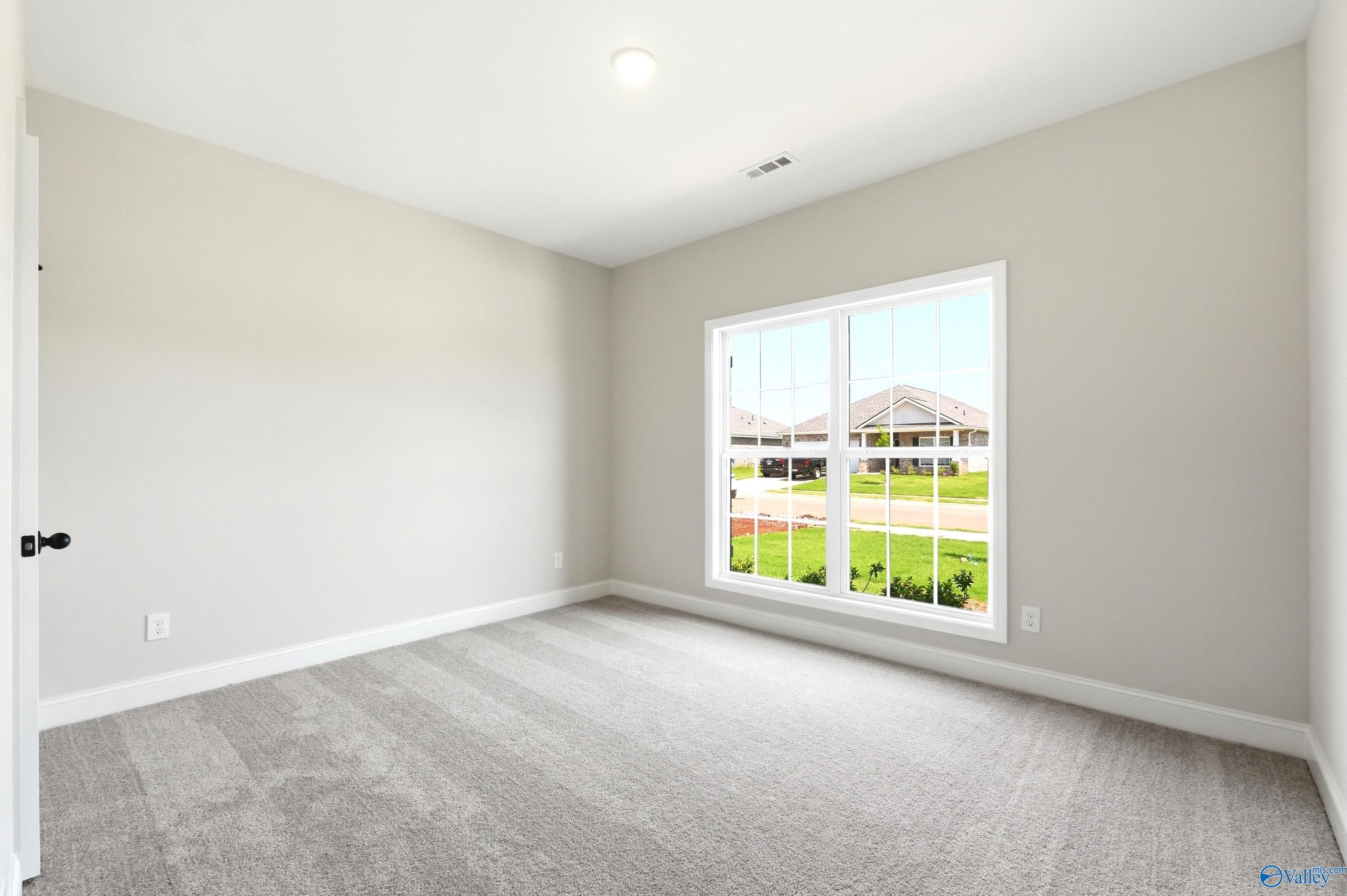 Bright carpeted bedroom with large windows in The Daphne floor plan by Davidson Homes in Clearview, Hazel Green, Alabama.