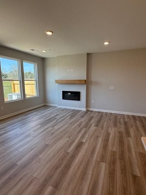 Cozy living room with modern gas fireplace, hardwood floors, and large windows in Davidson Homes The Durham D, Cumming, Georgia