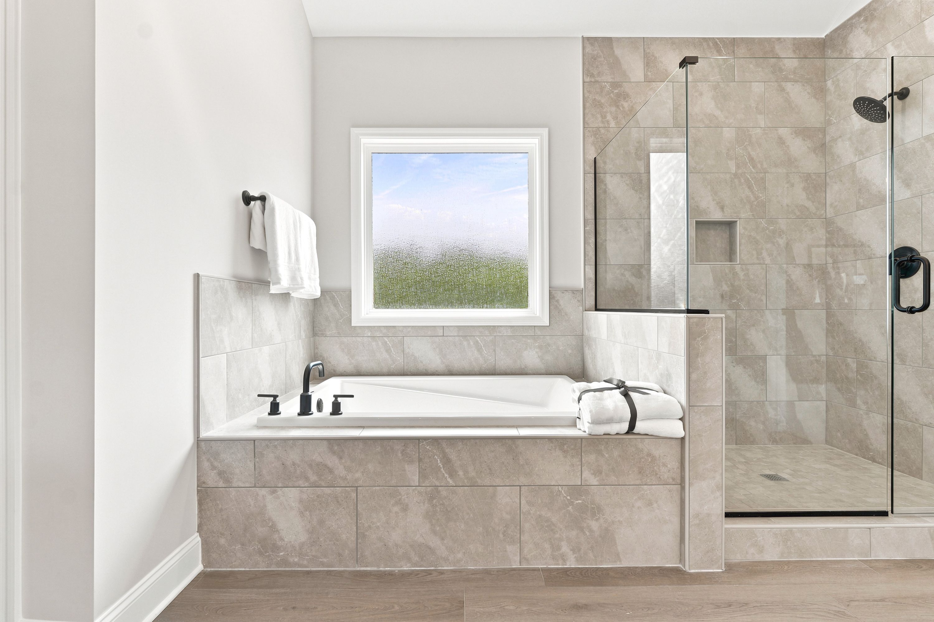 Luxurious primary bathroom at Riverton Preserve in Huntsville, AL featuring a soaking tub and glass-enclosed walk-in shower.